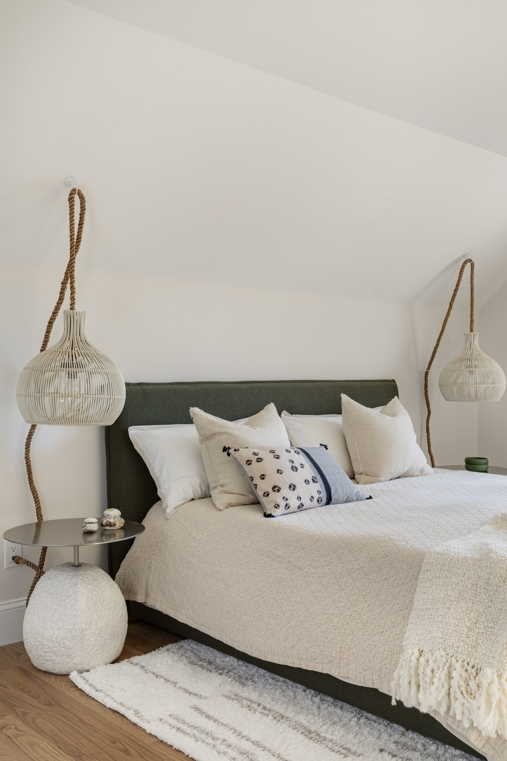 In the bedrooms of this Cape Cod home, the clients’ sentimental artwork was carefully reframed to give each piece a fresh, modern presence that complements the new design. Natural materials like wicker and rattan, gentle pops of green, and softly curved furniture tie the rooms to the coastal surroundings.