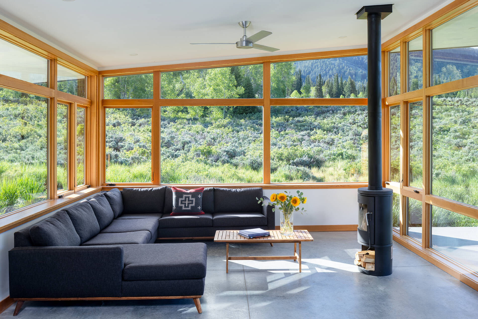 This living room in an off-grid cabin features southwest-facing windows that frame sweeping canyon views and fill the space with natural light.