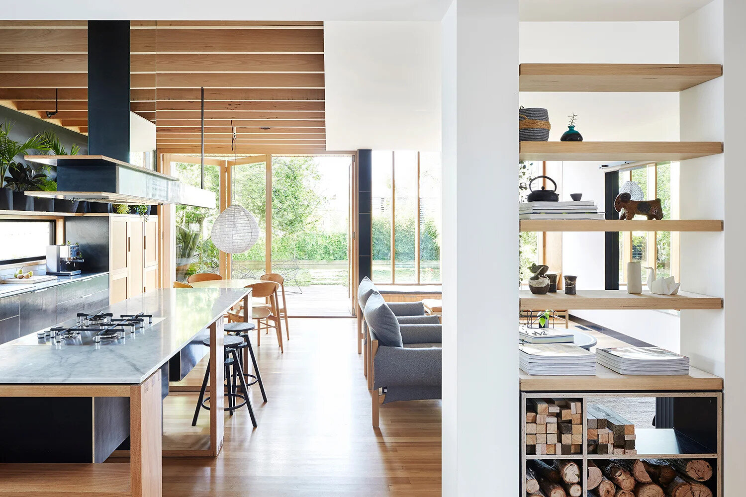 The living area is cozy and practical. Open shelving doubles as storage for stacked firewood, ready to feed the wood-burning fireplace. A large wall mirror creates a greater sense of space while cleverly hiding the television when it’s not in use.