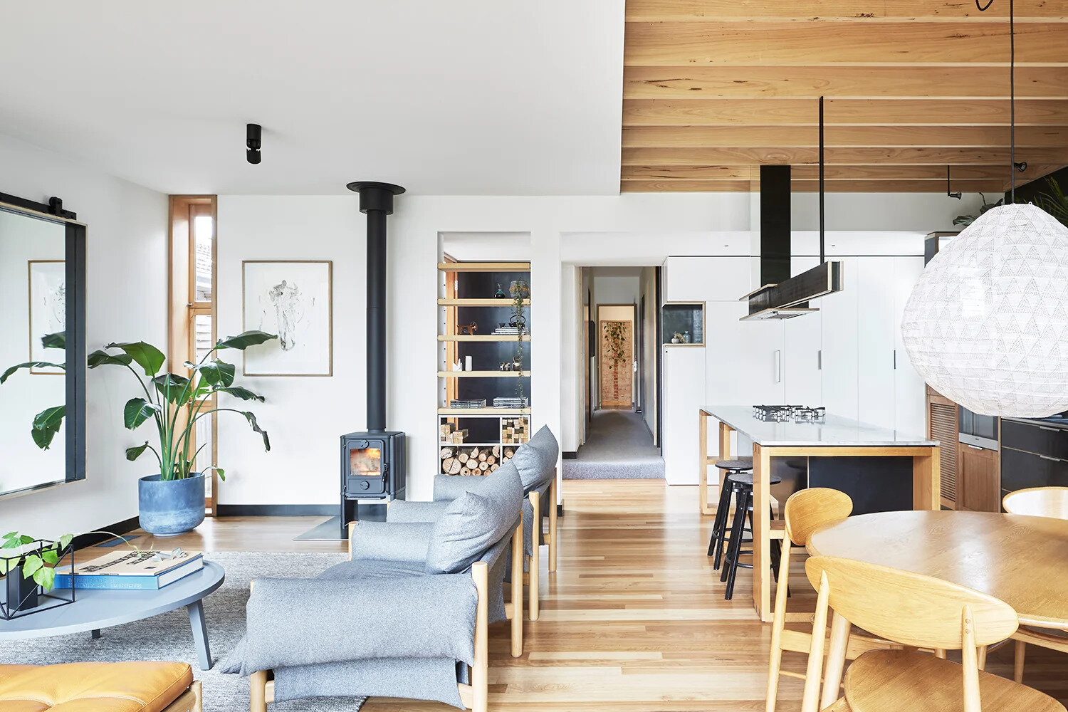 The living area is cozy and practical. Open shelving doubles as storage for stacked firewood, ready to feed the wood-burning fireplace. A large wall mirror creates a greater sense of space while cleverly hiding the television when it’s not in use.