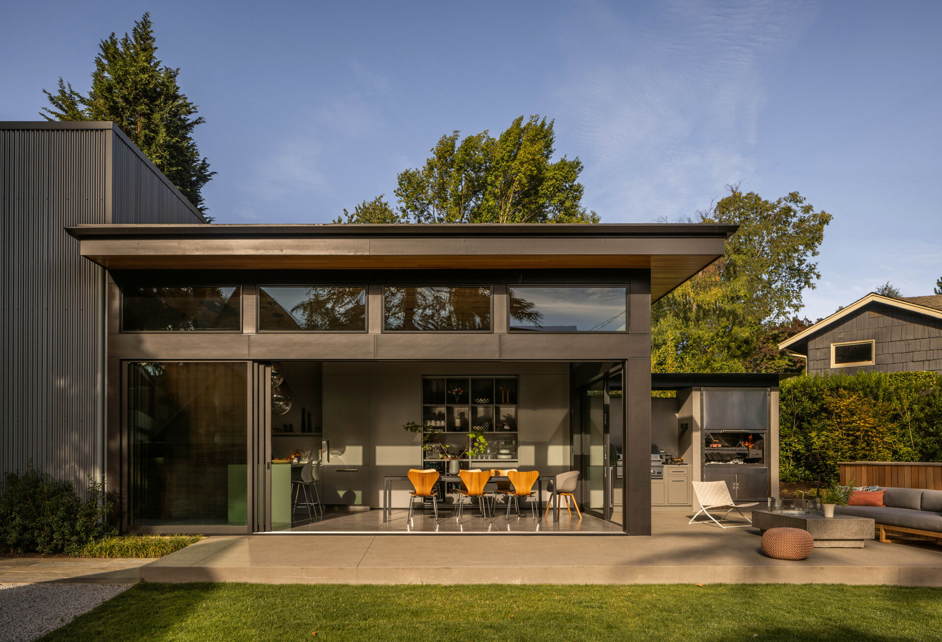Seamless indoor-outdoor living with sliding glass doors, lawn, fire table, and swim spa, perfect for family gatherings and entertaining.