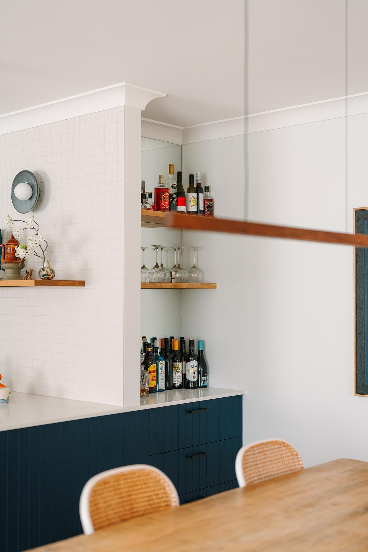 A former air-conditioning cavity was reimagined as a pocket gin bar, complete with warm wood shelves and a mirrored backing.