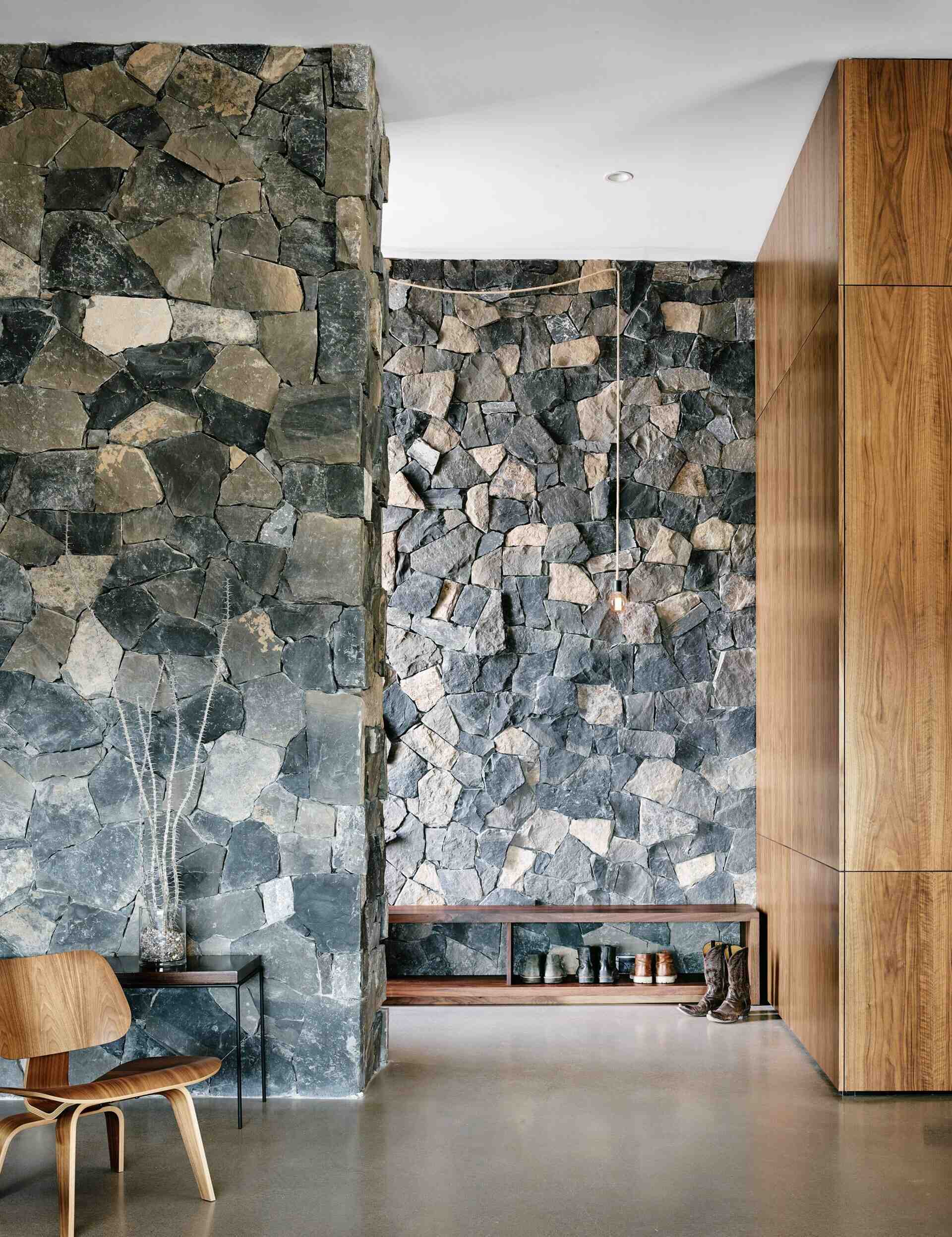 The entryway of this modern mountain home features walnut cabinets, stone walls, and rustic details.