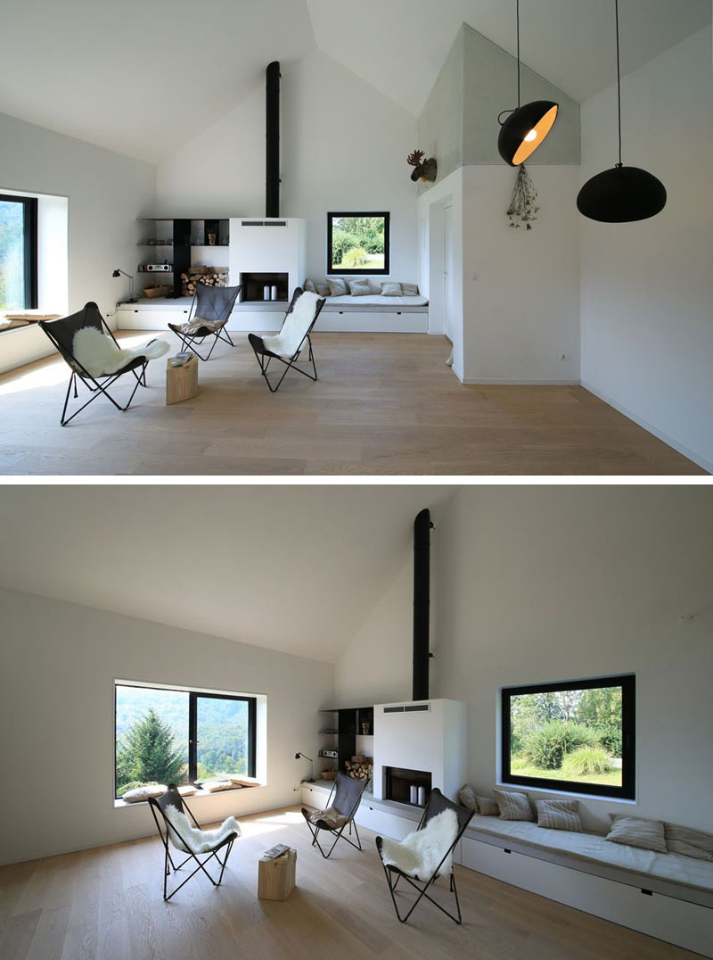 The living area feels minimalist yet warm, with built-in window seats and storage framing a fireplace. A simple palette of white, grey, and black makes the space feel open and airy.