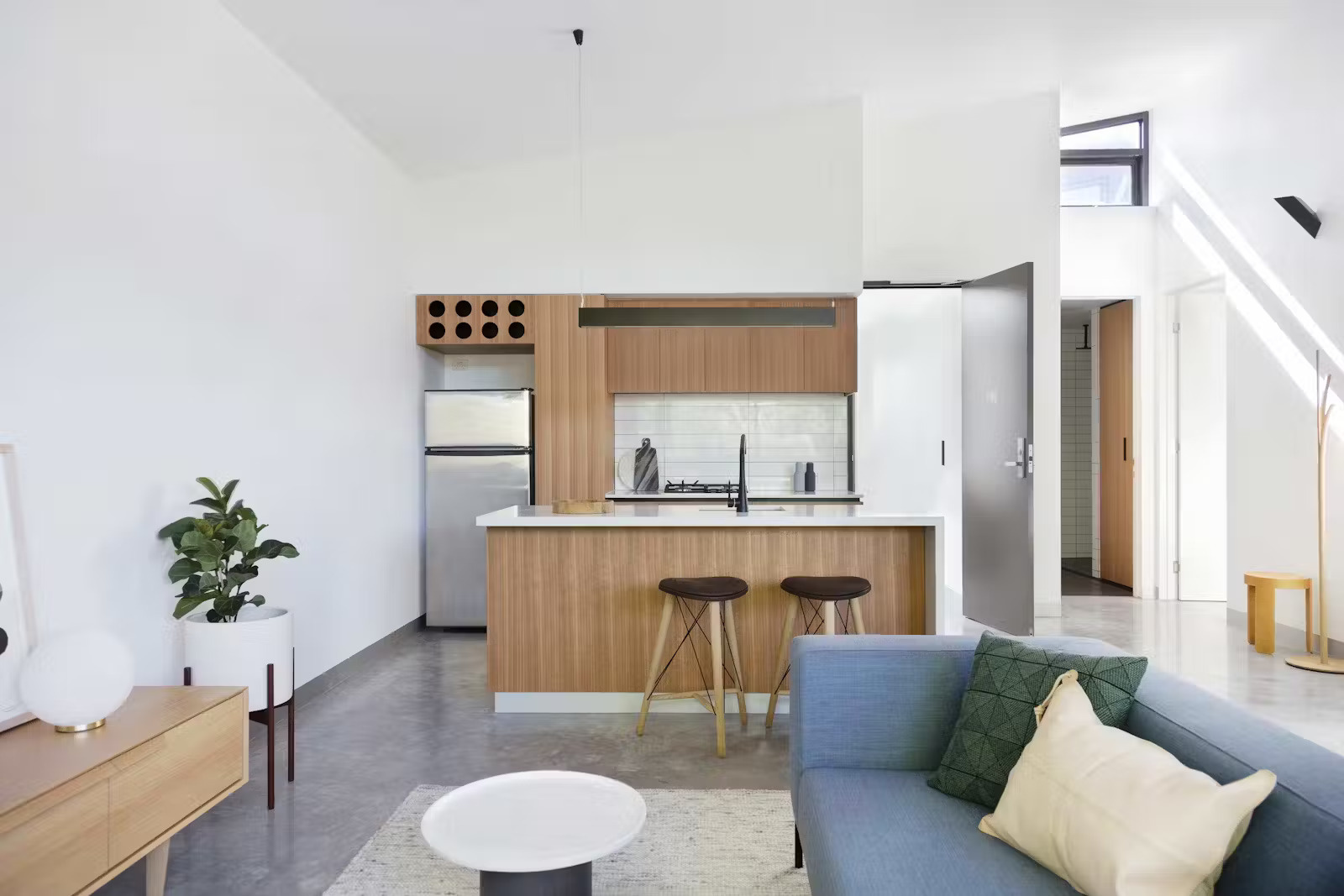 White walls and pale wood cabinetry keep these Melbourne apartments light, open, and calming, perfect for small-space living.