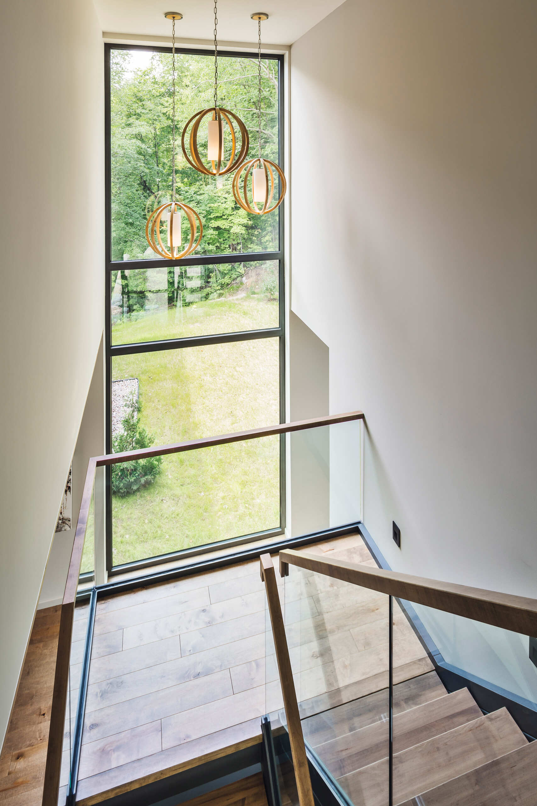 A glass-railed staircase topped with wood, is bathed in natural light connects all levels, keeping the interiors open and airy.