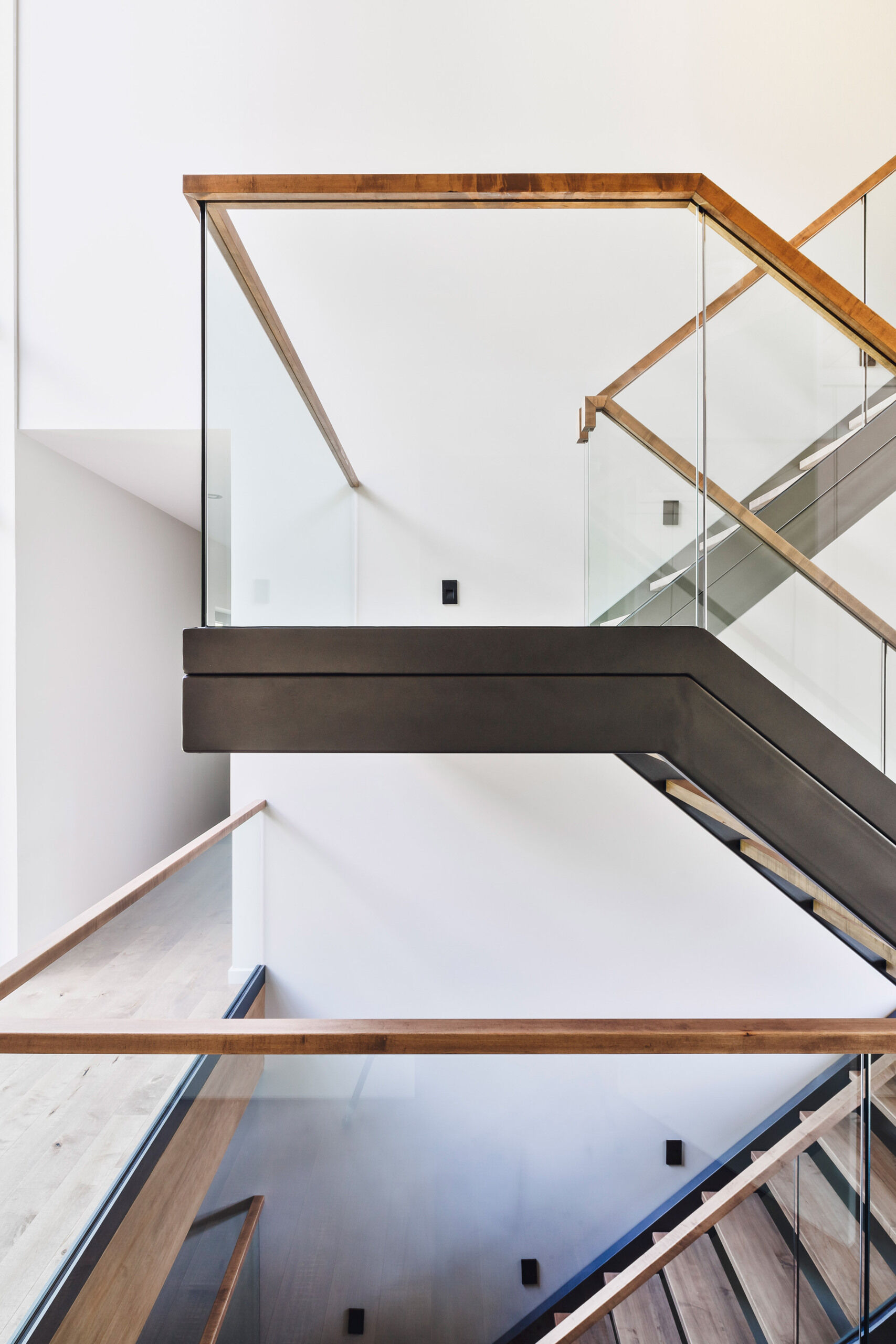 A glass-railed staircase topped with wood, is bathed in natural light connects all levels, keeping the interiors open and airy.
