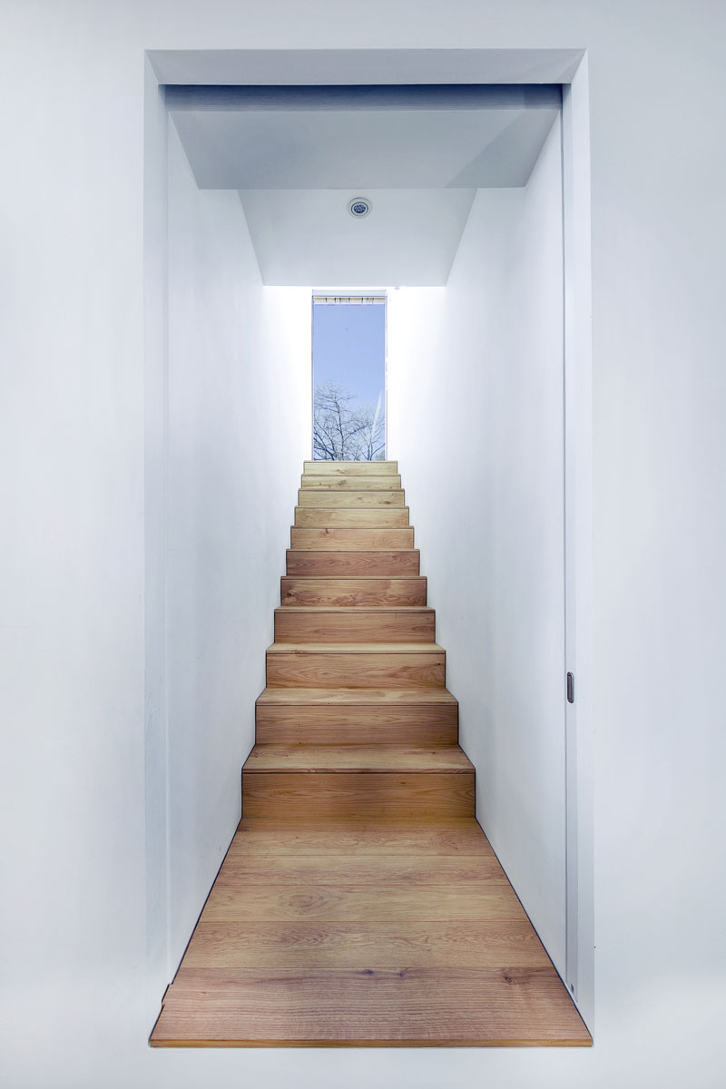 A timber staircase connects to the upper level, where light filters through in a calm, contemporary way.