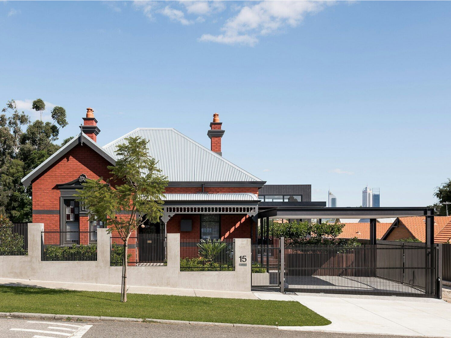 A striking contrast between old and new defines this Australian heritage home renovation, featuring a dark modern extension and sleek carport