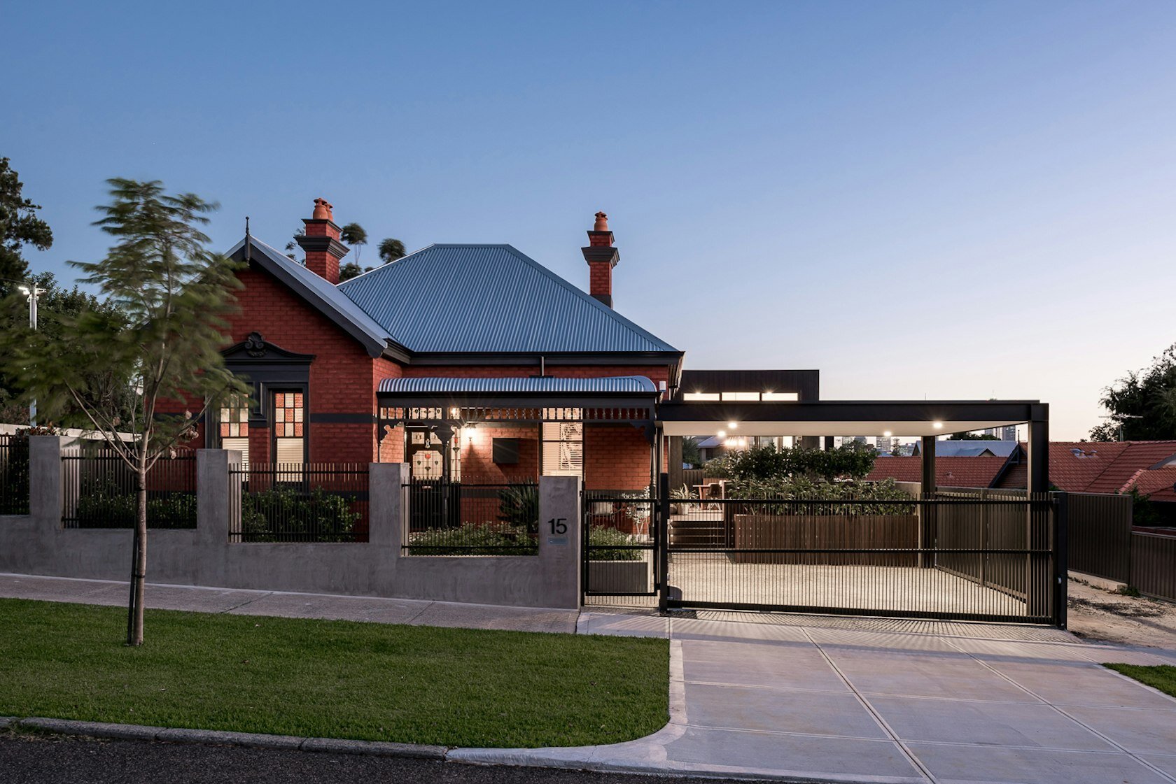 A striking contrast between old and new defines this Australian heritage home renovation, featuring a dark modern extension and sleek carport