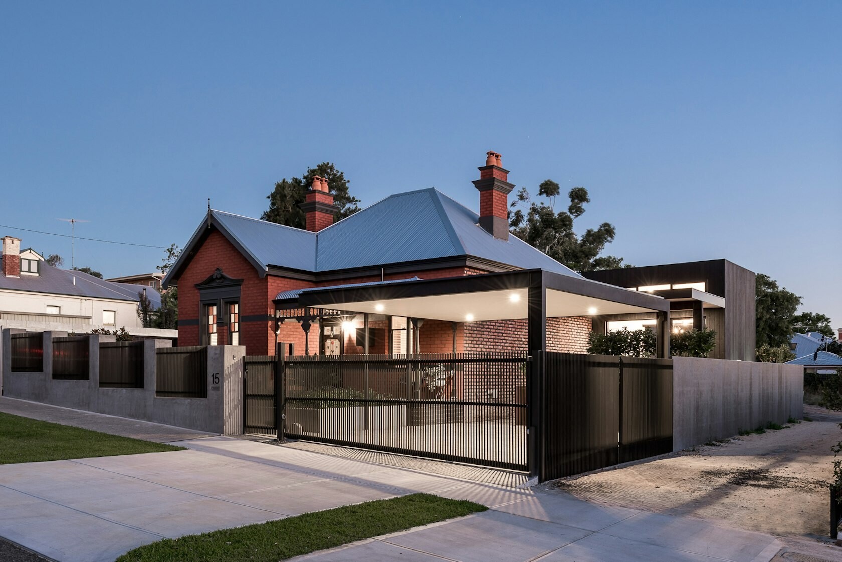 A striking contrast between old and new defines this Australian heritage home renovation, featuring a dark modern extension and sleek carport