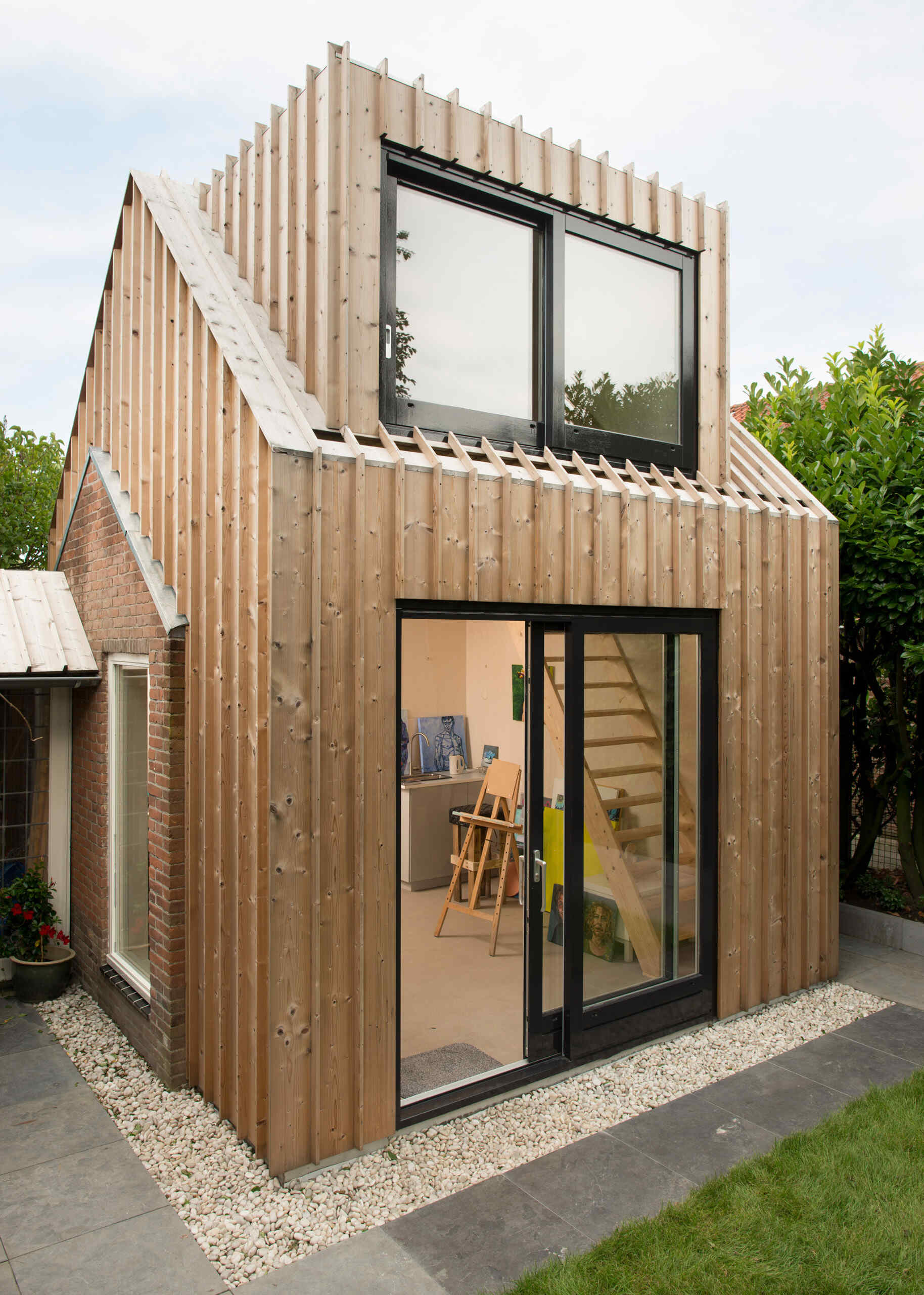 Old masonry walls and a new light wooden volume come together to create a warm, modern backyard art studio filled with natural light.