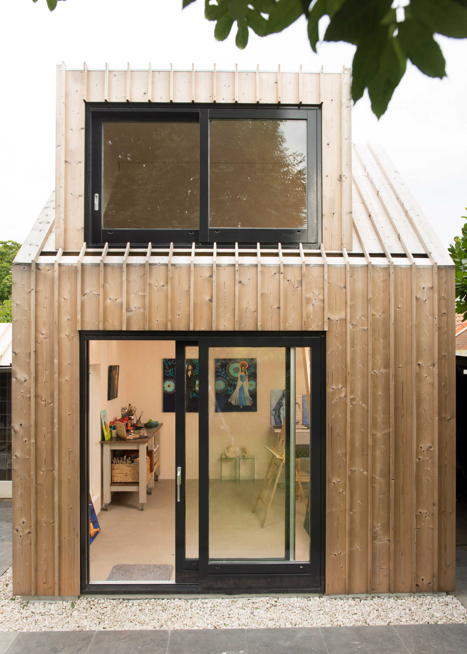 Old masonry walls and a new light wooden volume come together to create a warm, modern backyard art studio filled with natural light.