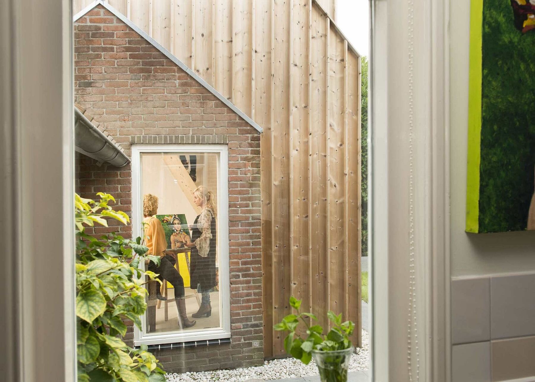 Old masonry walls and a new light wooden volume come together to create a warm, modern backyard art studio filled with natural light.