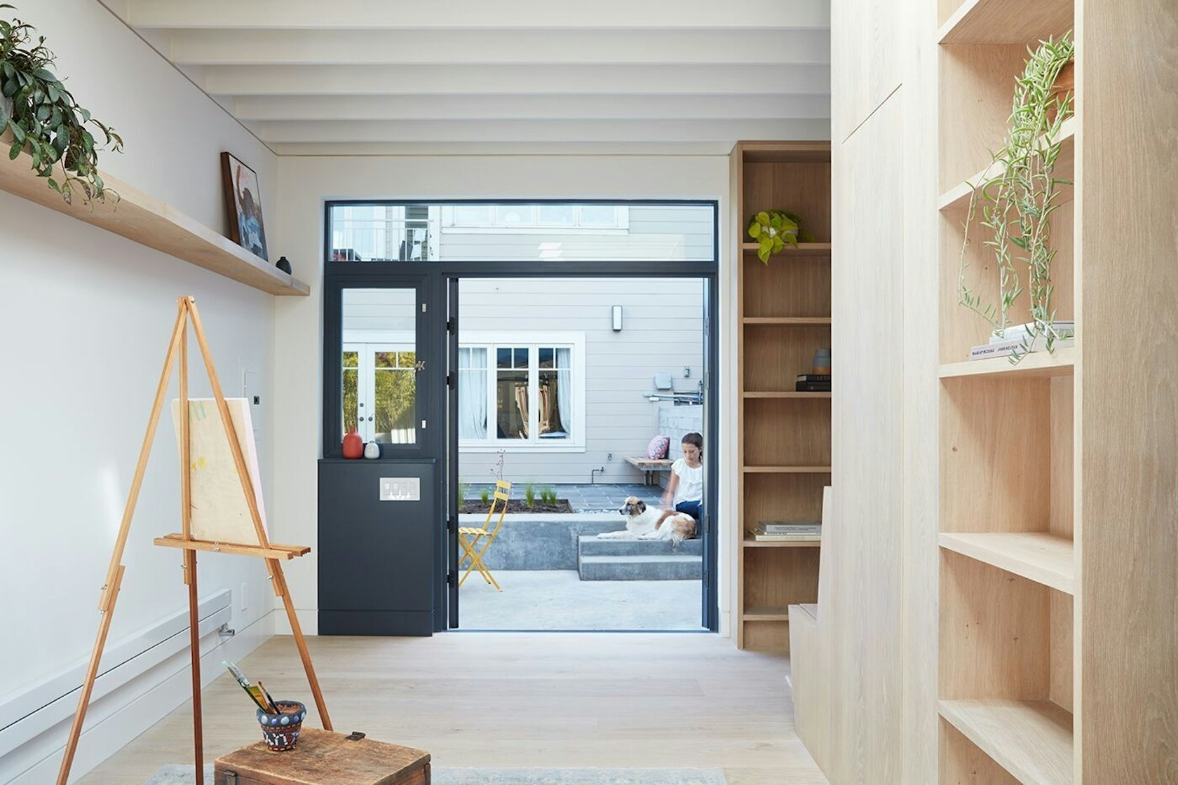 A cozy reading nook with a built-in bench and floor-to-ceiling bookshelves adds warmth and character to this small backyard studio.