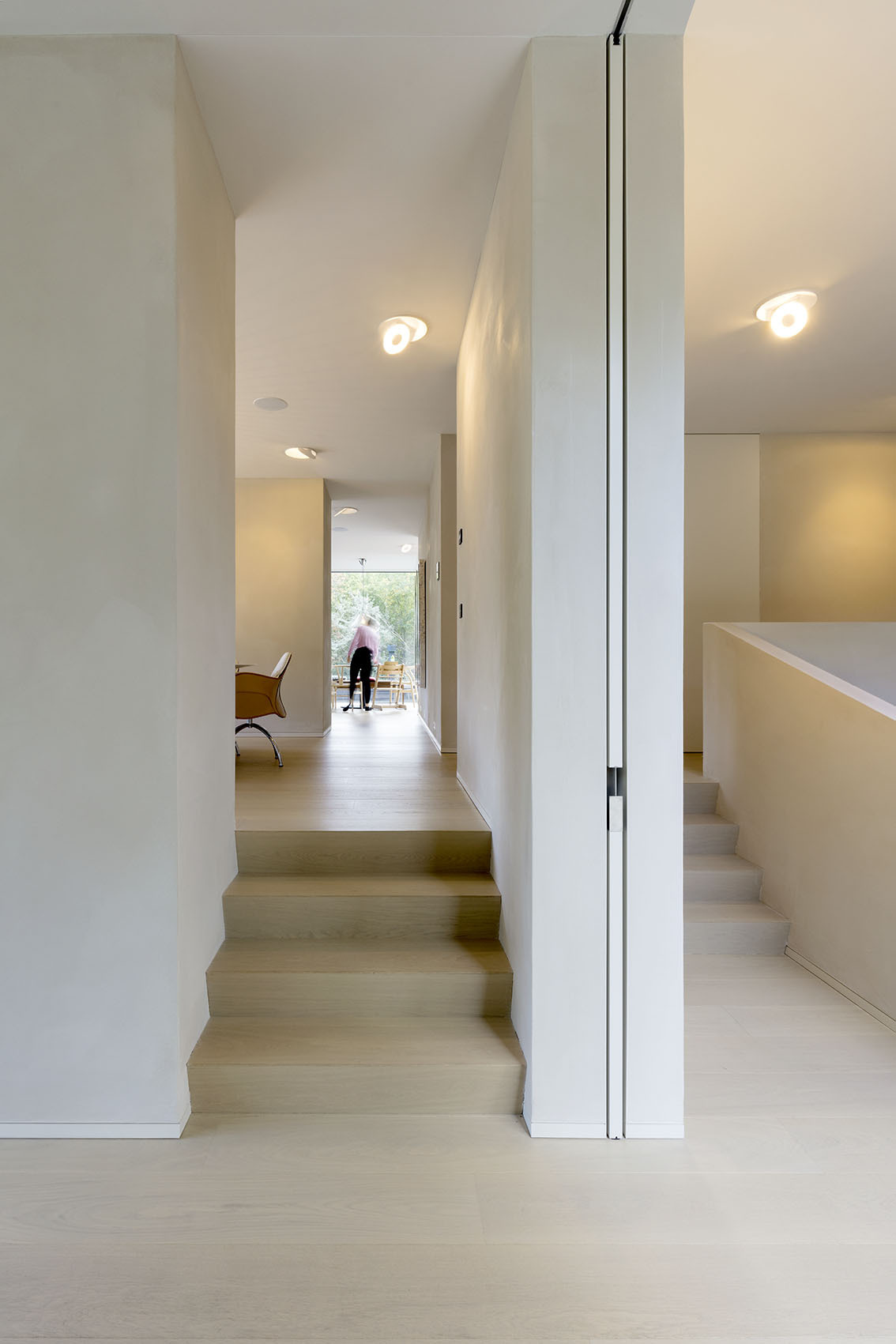 Stairs connect the home’s multiple levels, leading from the sunken ground floor to the open-plan living spaces above.
