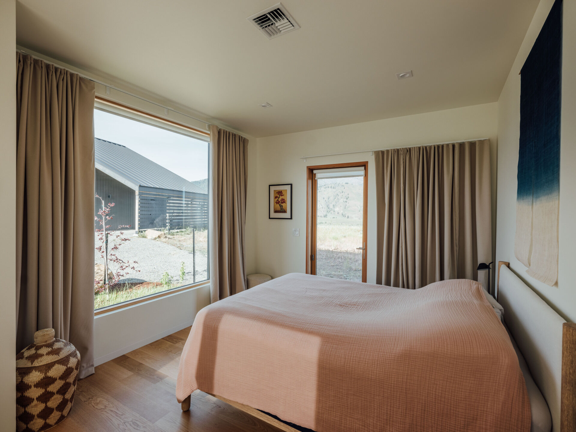 The bedroom captures a single ridge line through a perfectly scaled window. Minimal furniture and pale tones turn the view into art, setting the scene for complete rest.