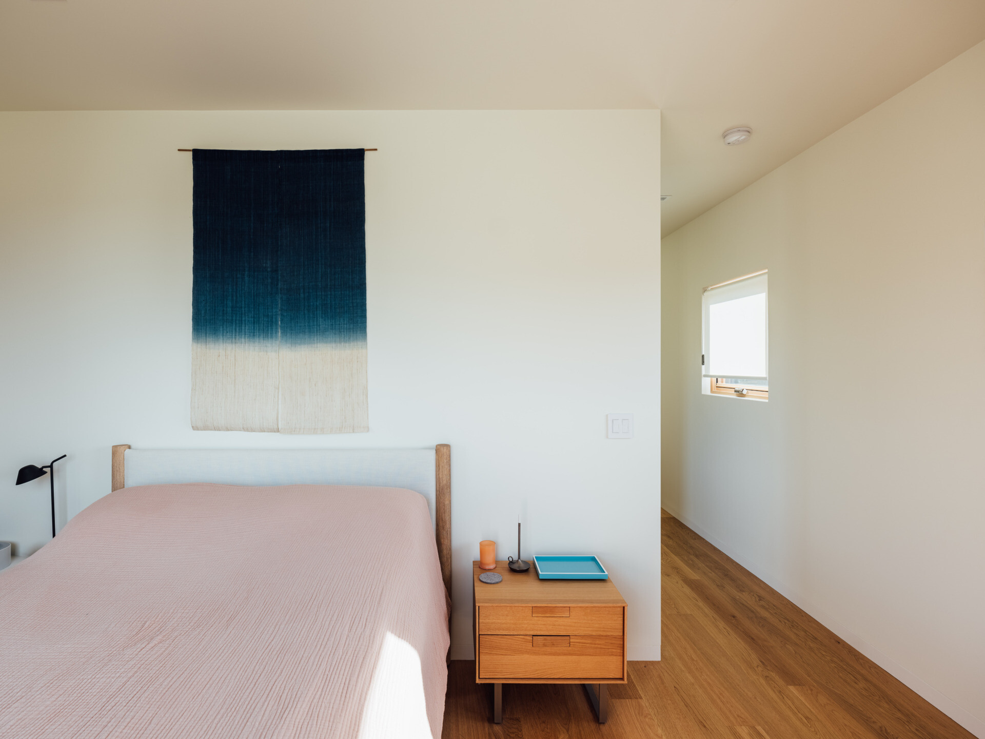 The bedroom captures a single ridge line through a perfectly scaled window. Minimal furniture and pale tones turn the view into art, setting the scene for complete rest.