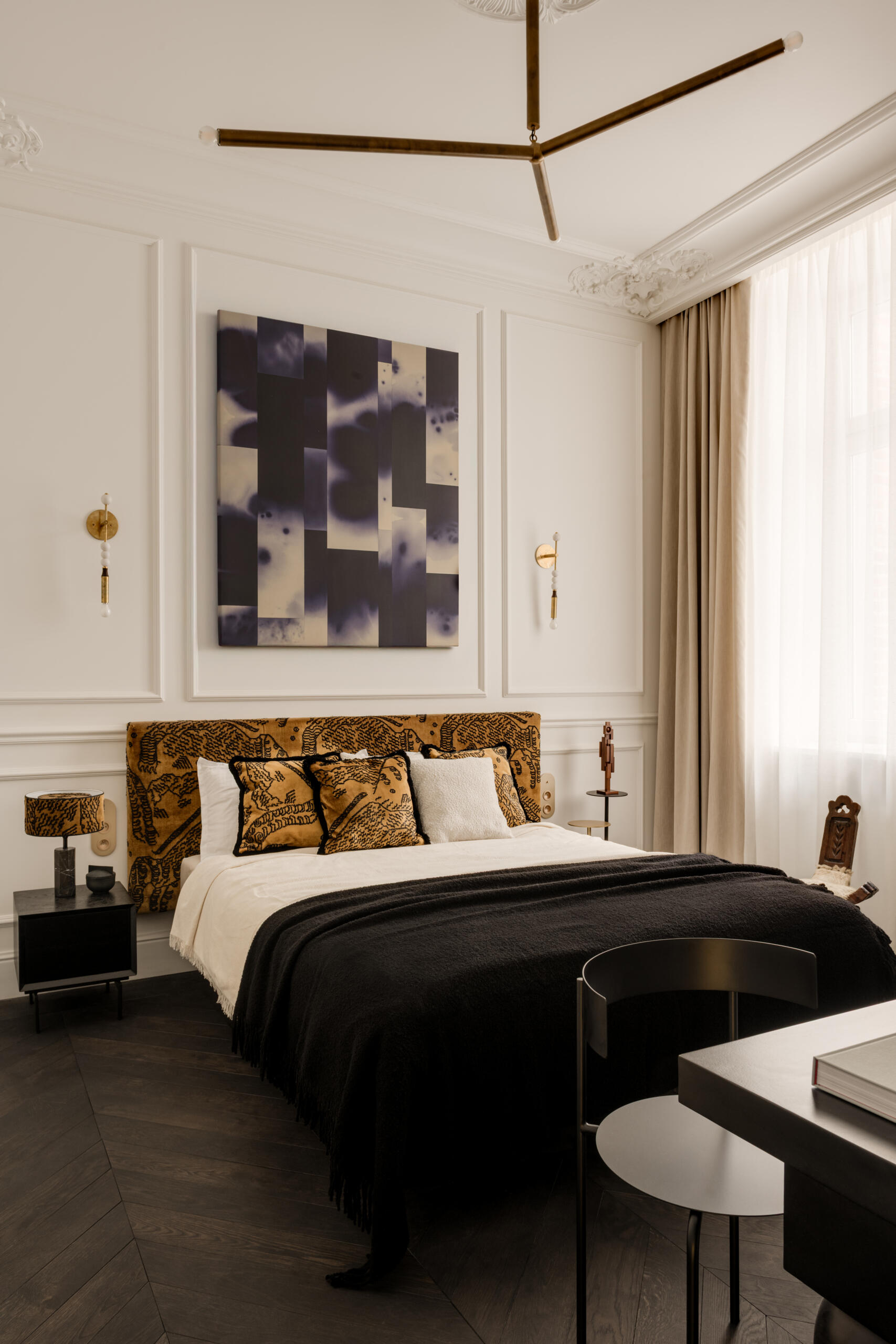 The bed appears to hover, supported by a hidden central leg. Wrapped in Dedar Milano fabric and accented by brass sconces, the bedroom feels serene and weightless. Artworks, sculptures, and handcrafted objects give it soul and quiet personality.