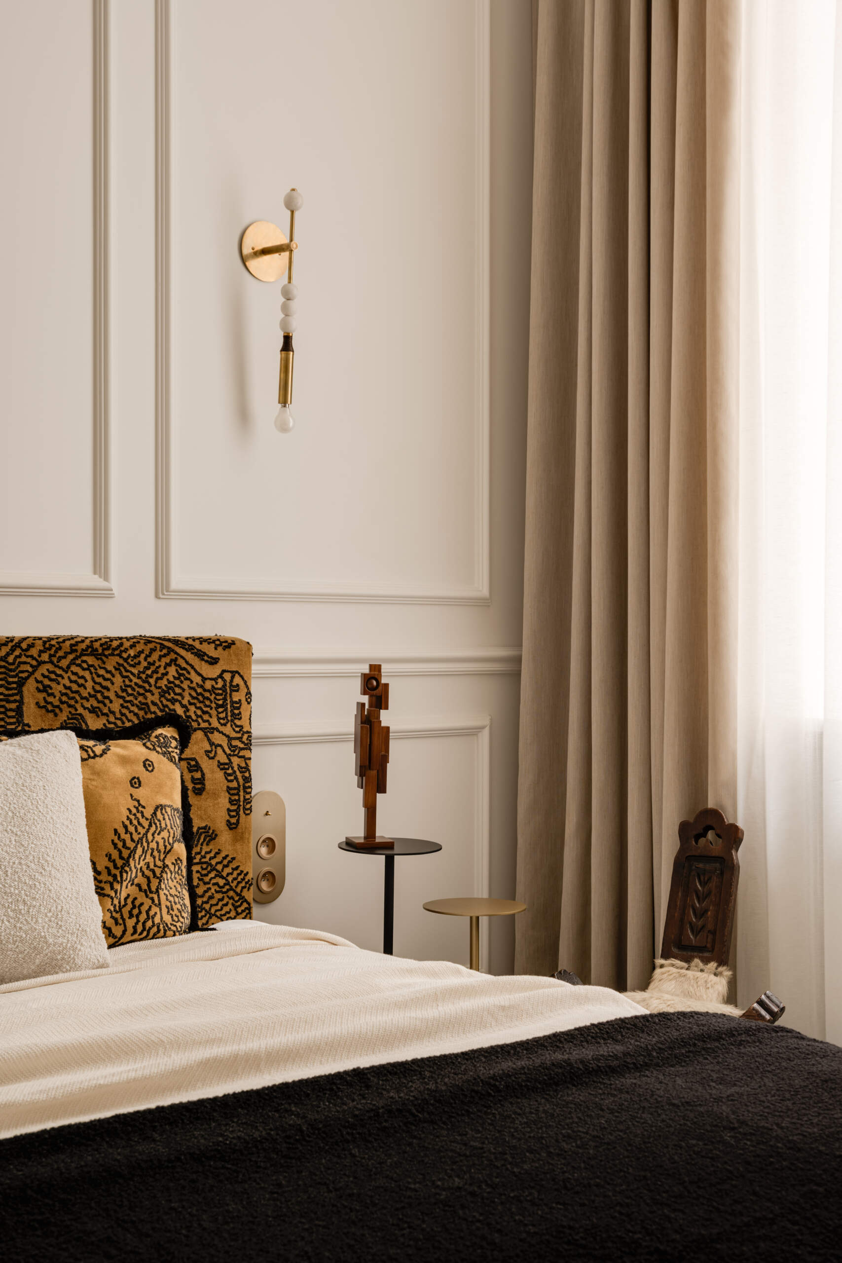 The bed appears to hover, supported by a hidden central leg. Wrapped in Dedar Milano fabric and accented by brass sconces, the bedroom feels serene and weightless. Artworks, sculptures, and handcrafted objects give it soul and quiet personality.