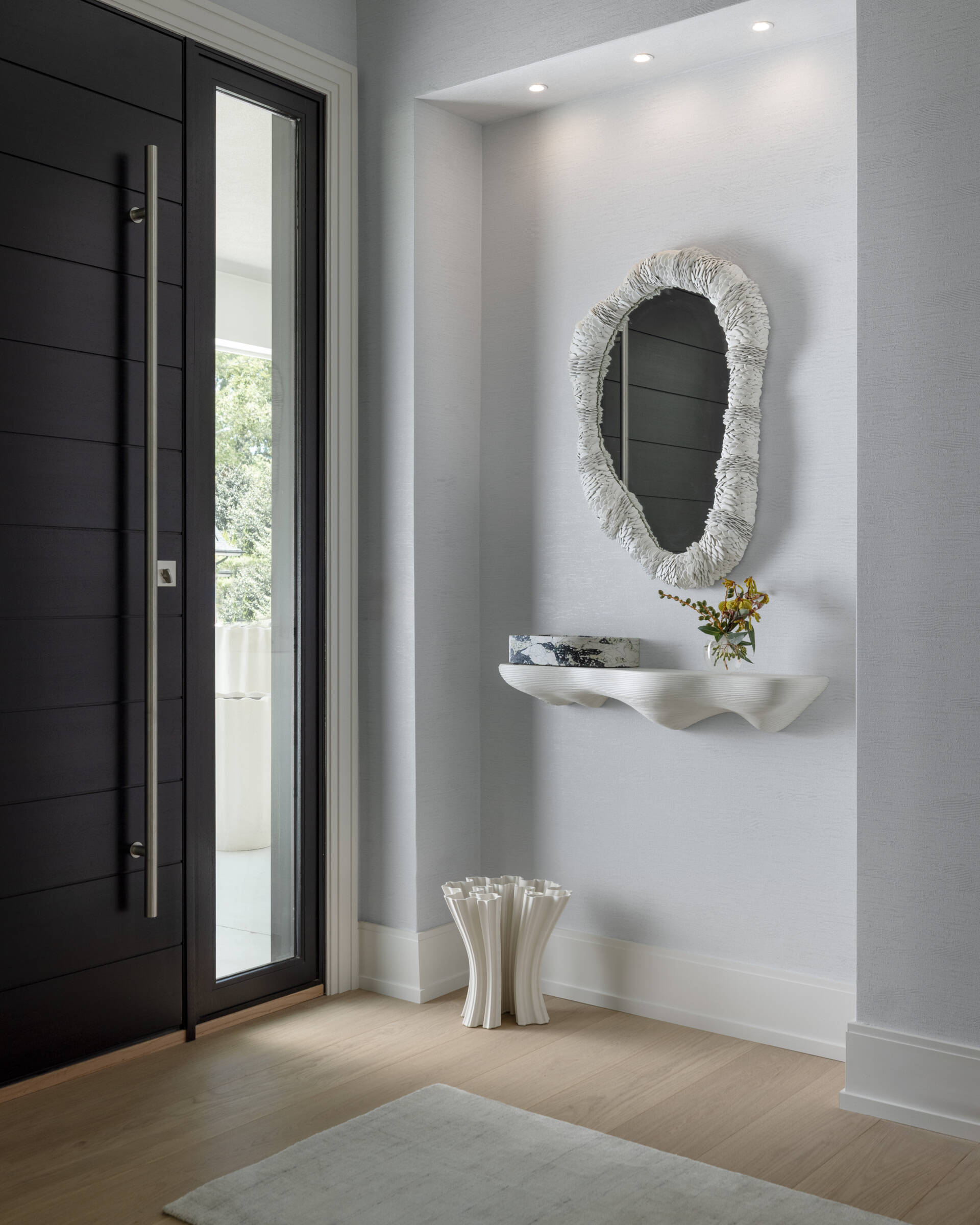 The entryway keeps it simple and serene. Clean-lined storage, a statement mirror, colorful artwork, and warm wood underfoot say you can exhale now. It is softly styled rather than showy, which makes the rest of the tour feel even more considered.