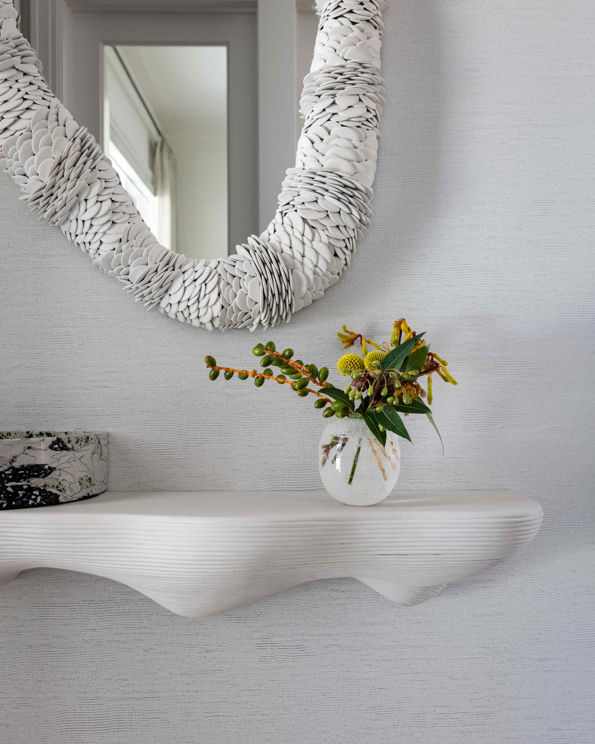 The entryway keeps it simple and serene. Clean-lined storage, a statement mirror, colorful artwork, and warm wood underfoot say you can exhale now. It is softly styled rather than showy, which makes the rest of the tour feel even more considered.