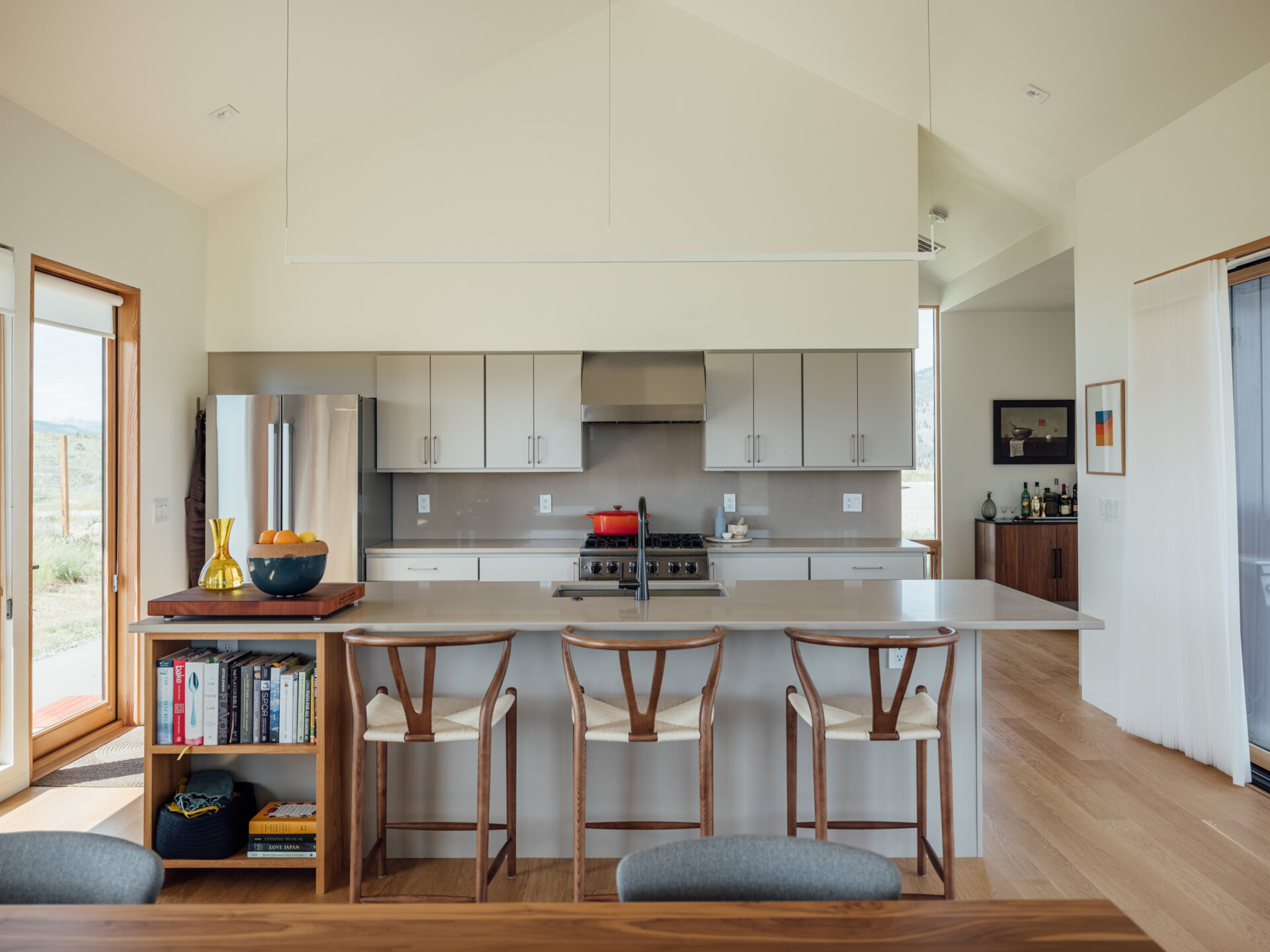 A serene gray kitchen opens to the valley beyond. Natural light glides across the island and cabinetry, revealing the home’s balance of modern clarity and rustic comfort.