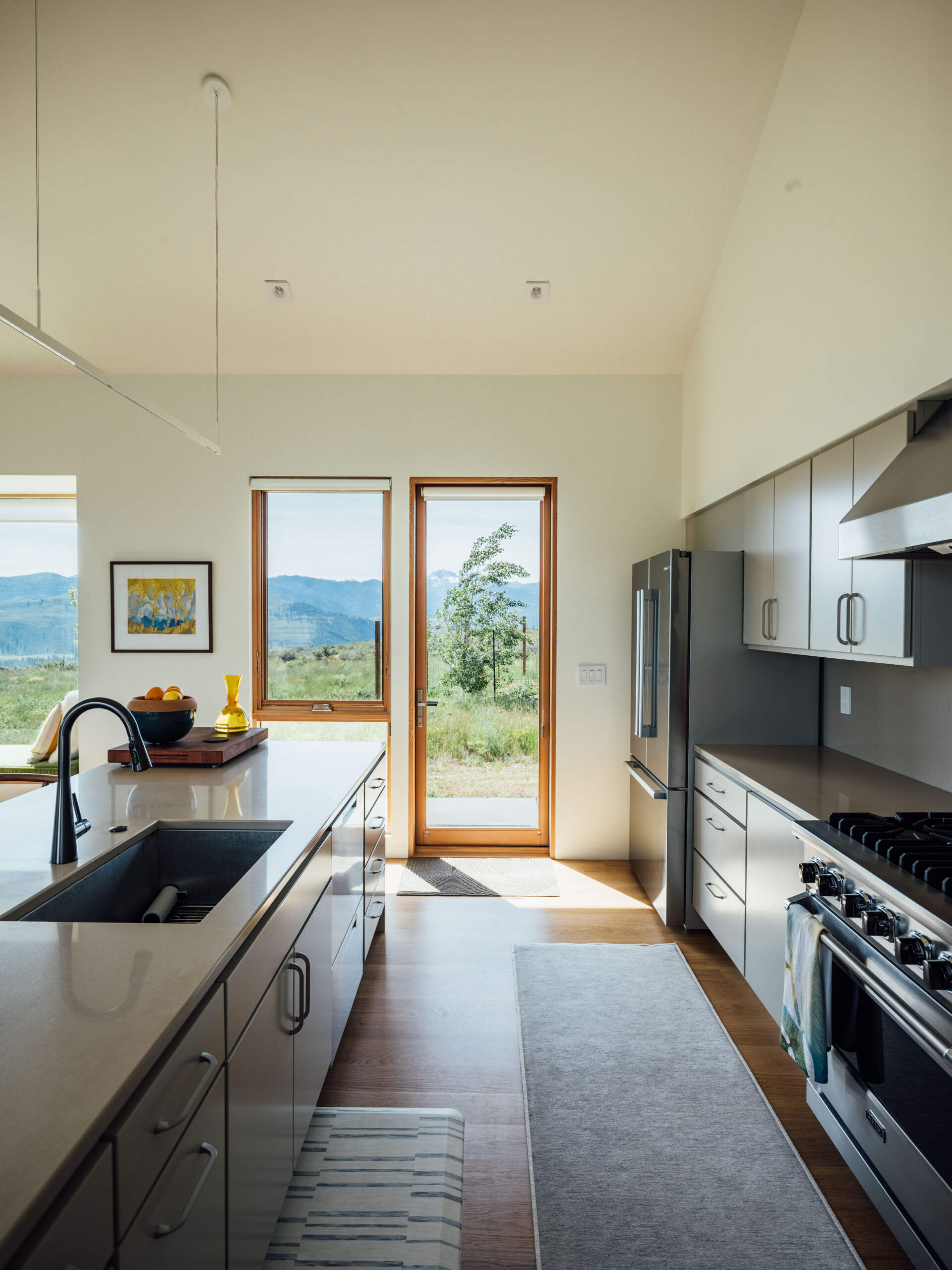 A serene gray kitchen opens to the valley beyond. Natural light glides across the island and cabinetry, revealing the home’s balance of modern clarity and rustic comfort.