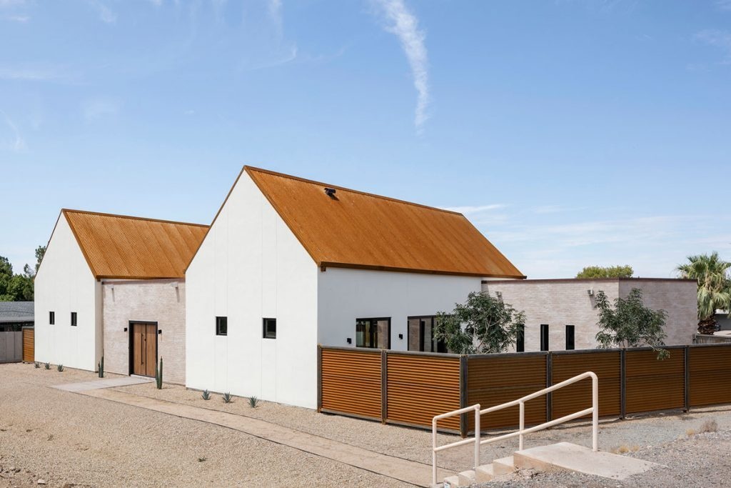 A modern desert home in Phoenix blends mission-inspired forms, white brick walls, and a rusted metal roof to capture Arizona’s light and history.