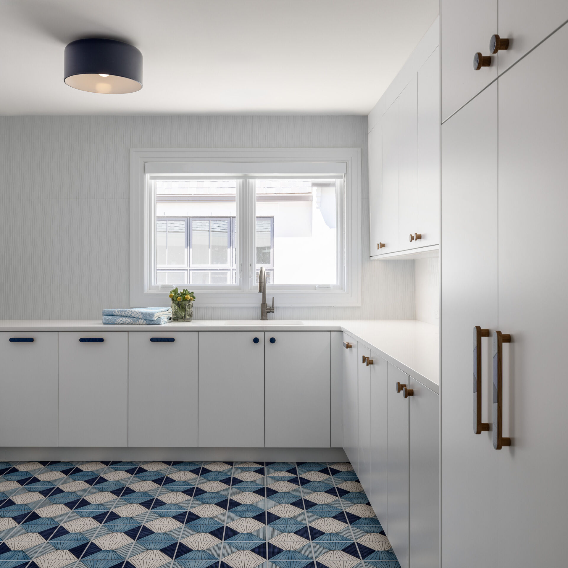 Patterned tile brings a cheerful kick to the laundry. Built-ins keep mess contained in the mudroom. Benches, hooks, and closed storage make coming and going painless. It is the kind of practical luxury that makes a house feel tailored.