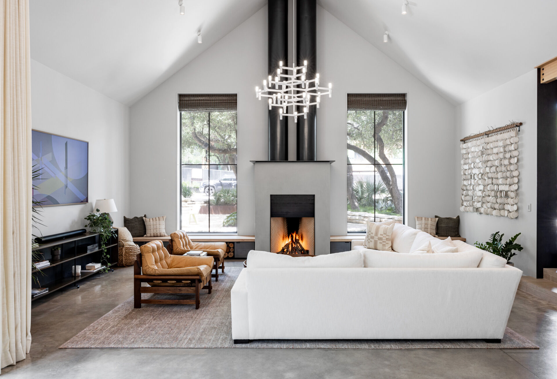 The living room frames the preserved oak tree, while a fireplace with custom wood and steel benches on either side, expands the seating options and providing firewood storage.
