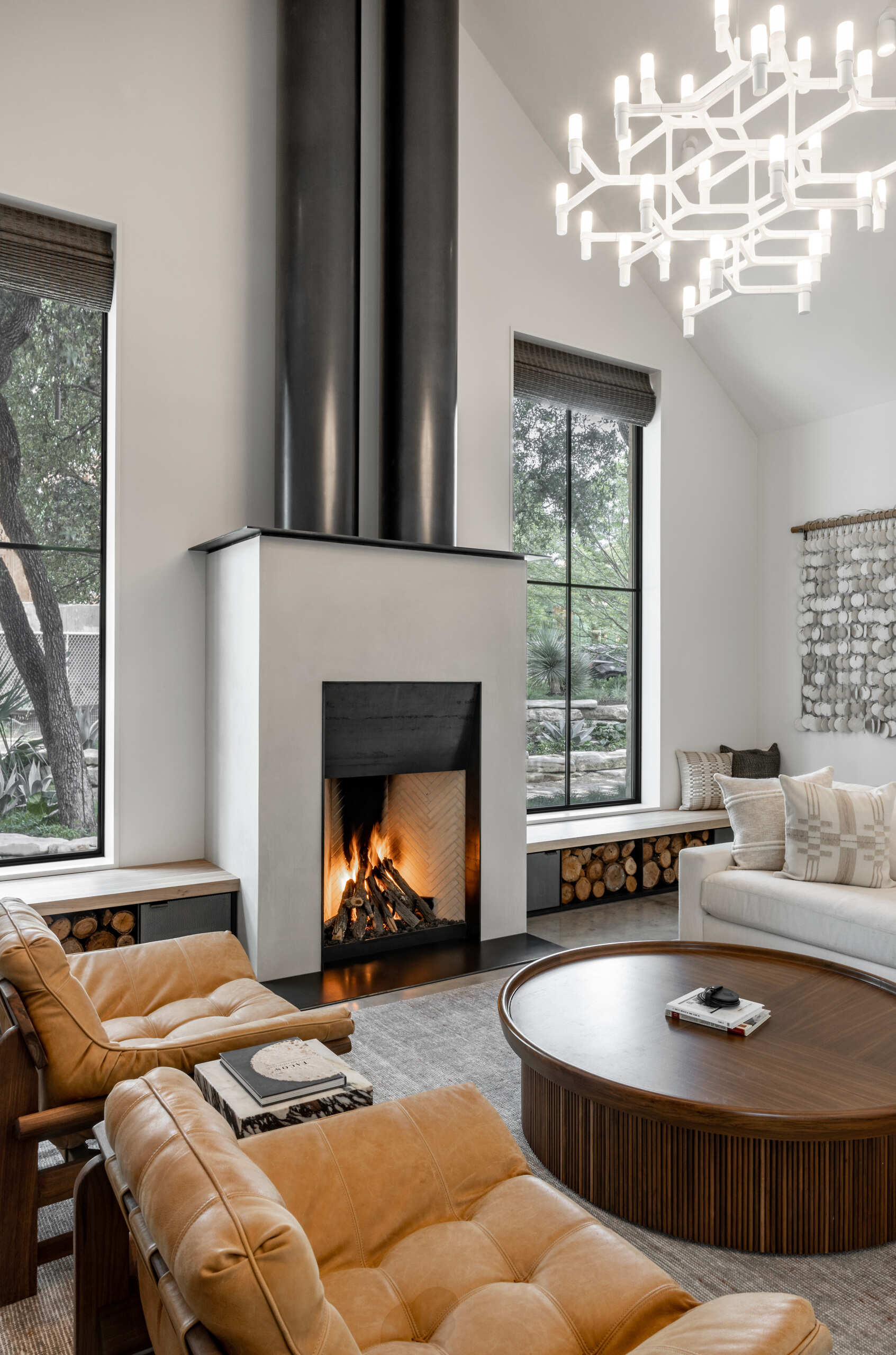 The living room frames the preserved oak tree, while a fireplace with custom wood and steel benches on either side, expands the seating options and providing firewood storage.