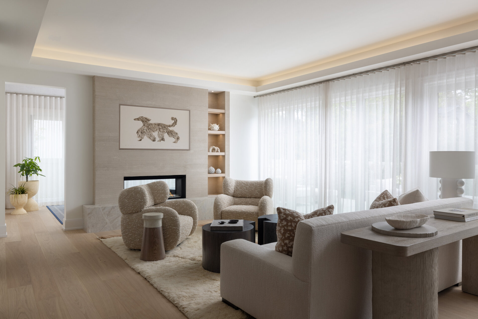 Seating is deep and inviting. Bouclé and bouclé-like textures keep things plush. A clean-lined media wall disappears when you want a quiet moment. The color story stays in that restful zone between cream and stone, with wood accents for warmth. You can feel the every-room-feels-like-a-spa brief coming to life here.