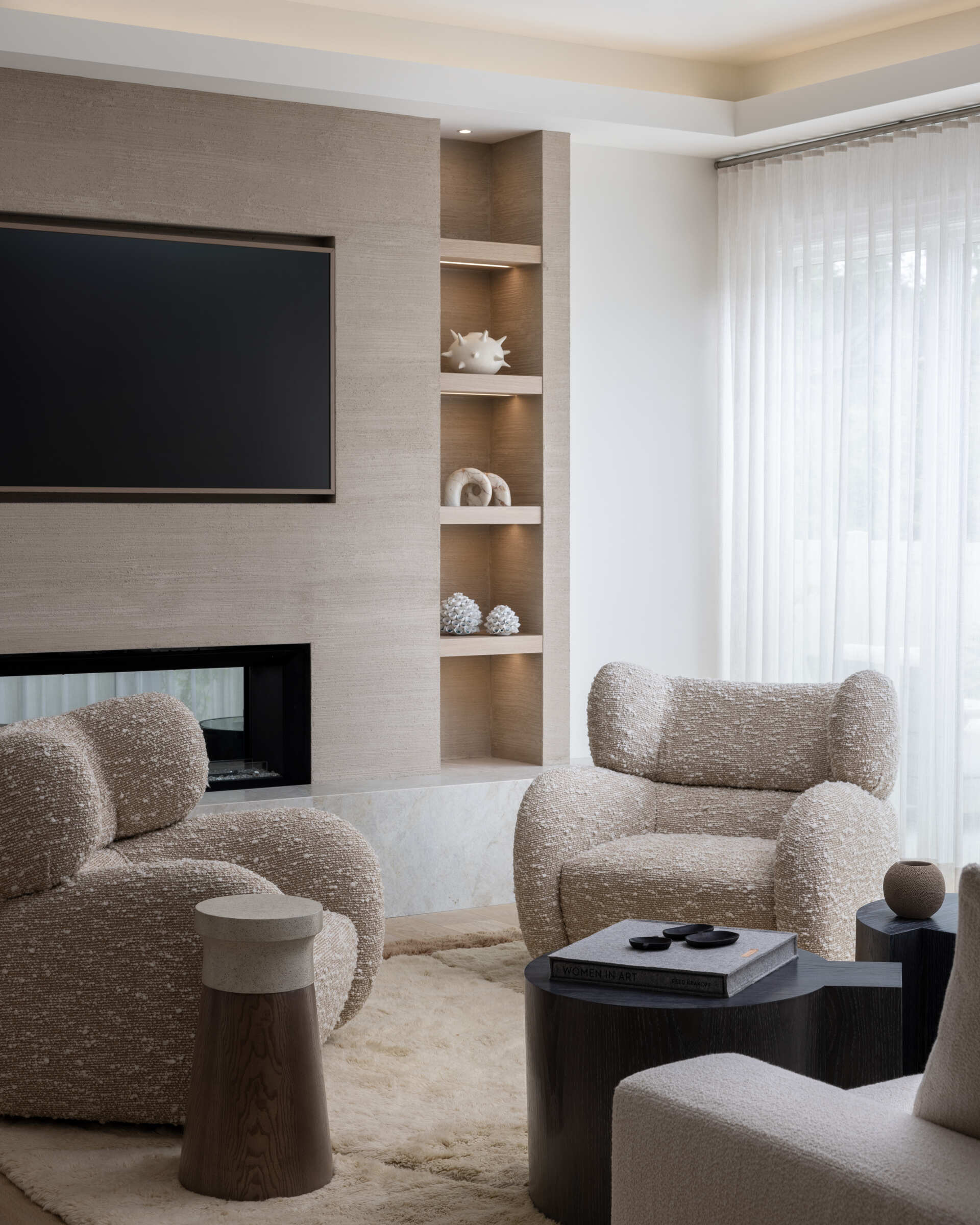 Seating is deep and inviting. Bouclé and bouclé-like textures keep things plush. A clean-lined media wall disappears when you want a quiet moment. The color story stays in that restful zone between cream and stone, with wood accents for warmth. You can feel the every-room-feels-like-a-spa brief coming to life here.