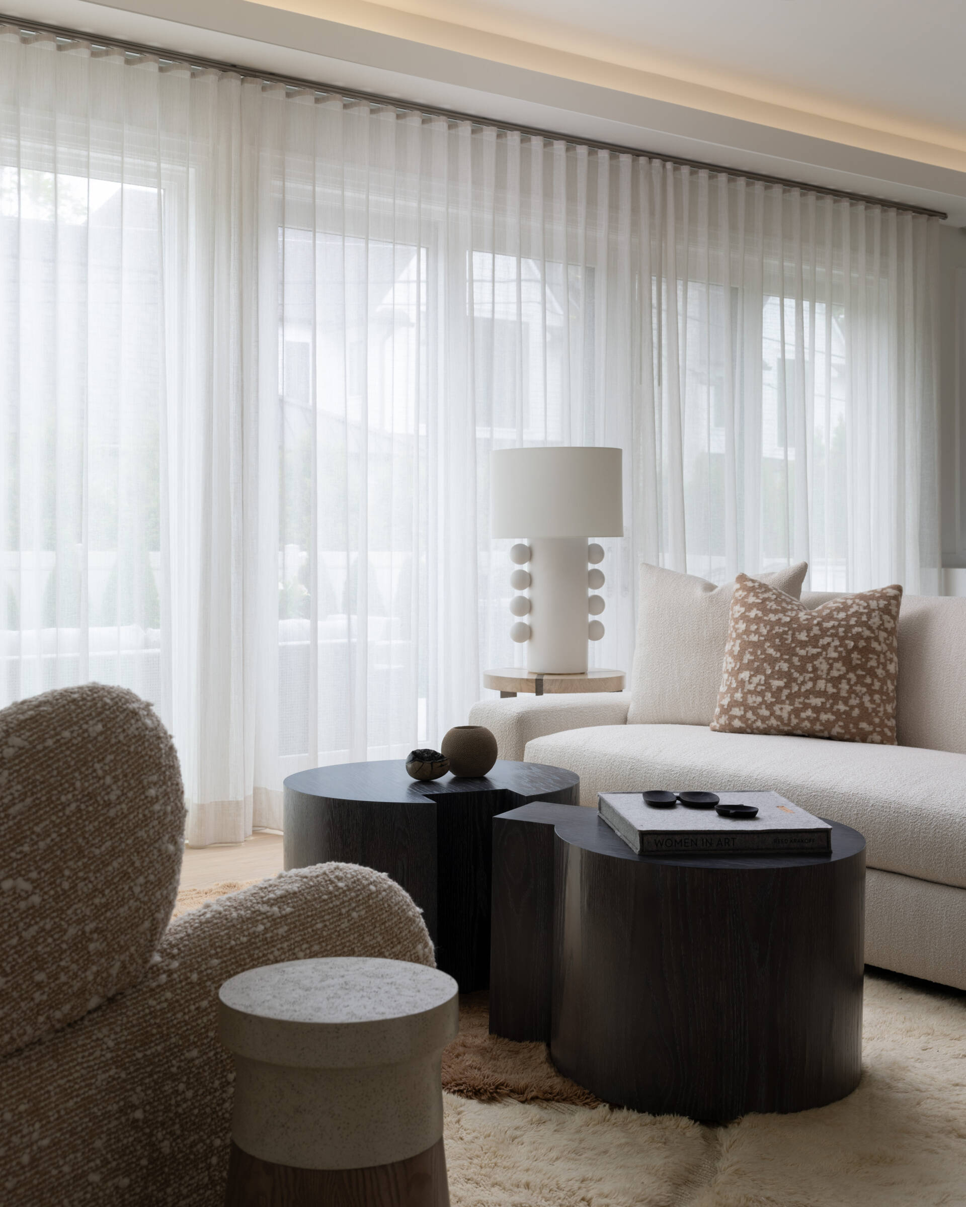 Seating is deep and inviting. Bouclé and bouclé-like textures keep things plush. A clean-lined media wall disappears when you want a quiet moment. The color story stays in that restful zone between cream and stone, with wood accents for warmth. You can feel the every-room-feels-like-a-spa brief coming to life here.