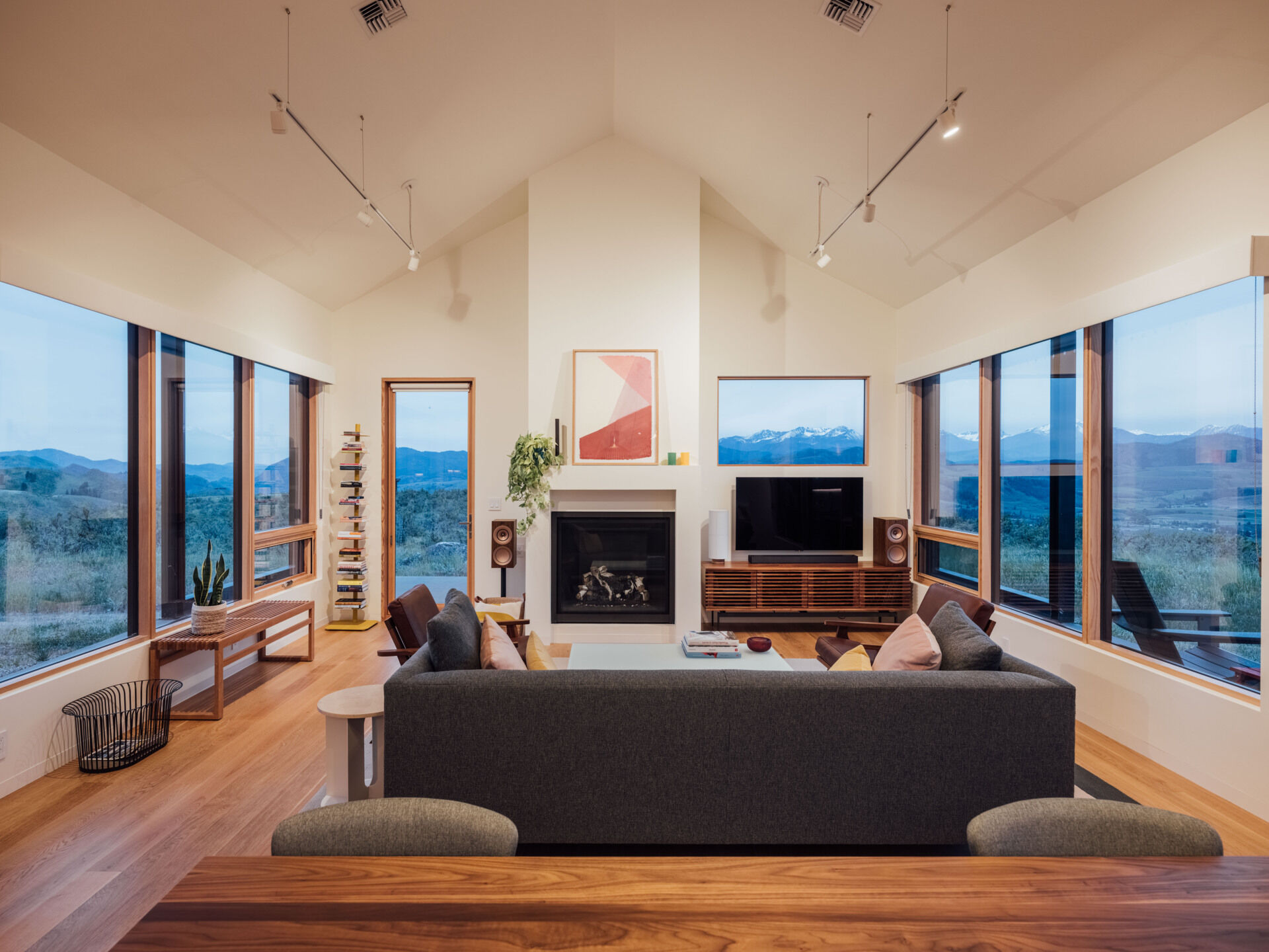 The living room balances warmth and restraint. Gray tones and timber finishes let the landscape take the lead, while the nearby window seat adds a lived-in, human touch to the architecture.