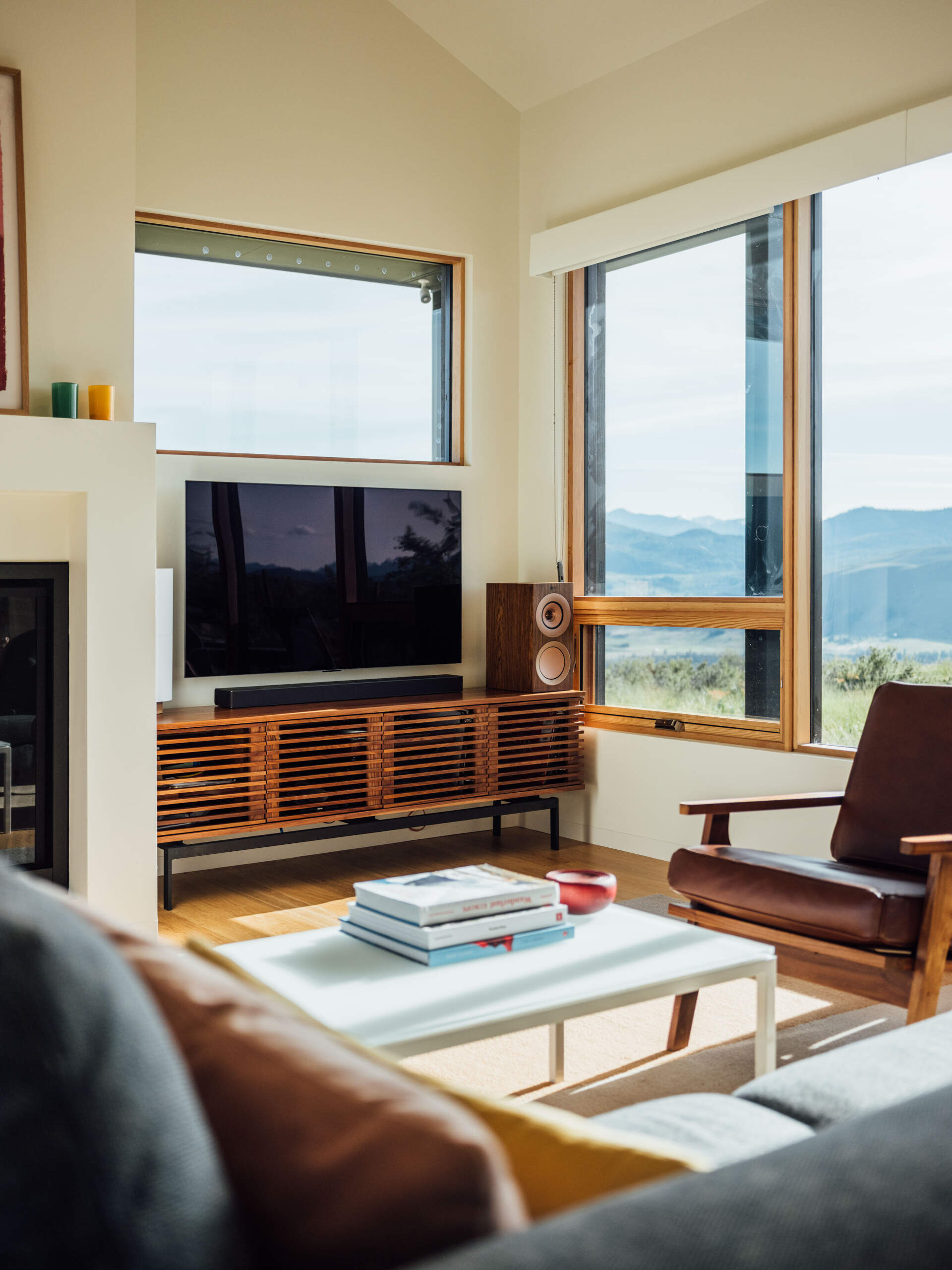 The living room balances warmth and restraint. Gray tones and timber finishes let the landscape take the lead, while the nearby window seat adds a lived-in, human touch to the architecture.