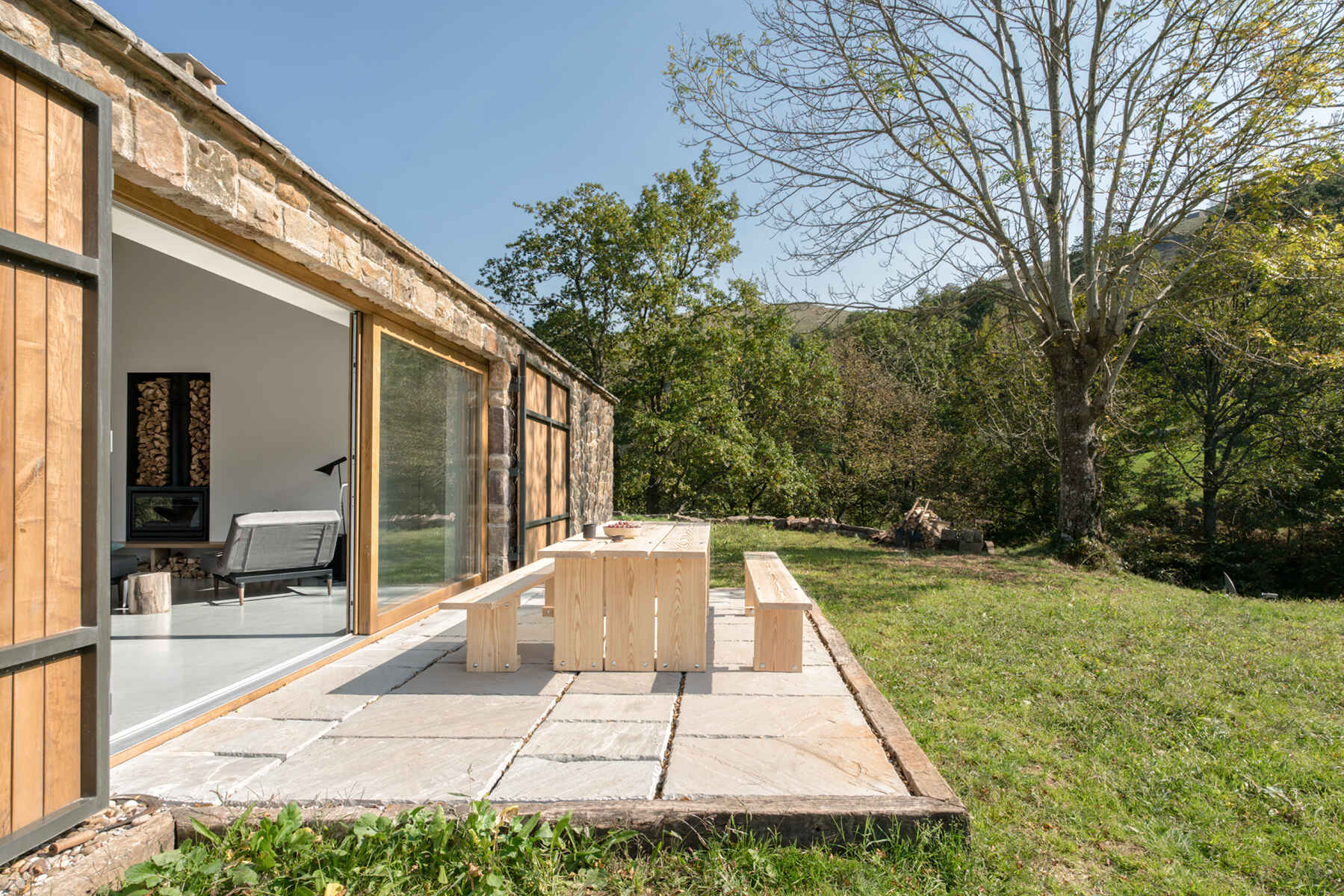 A stone cottage with sliding glass doors that open to a patio.