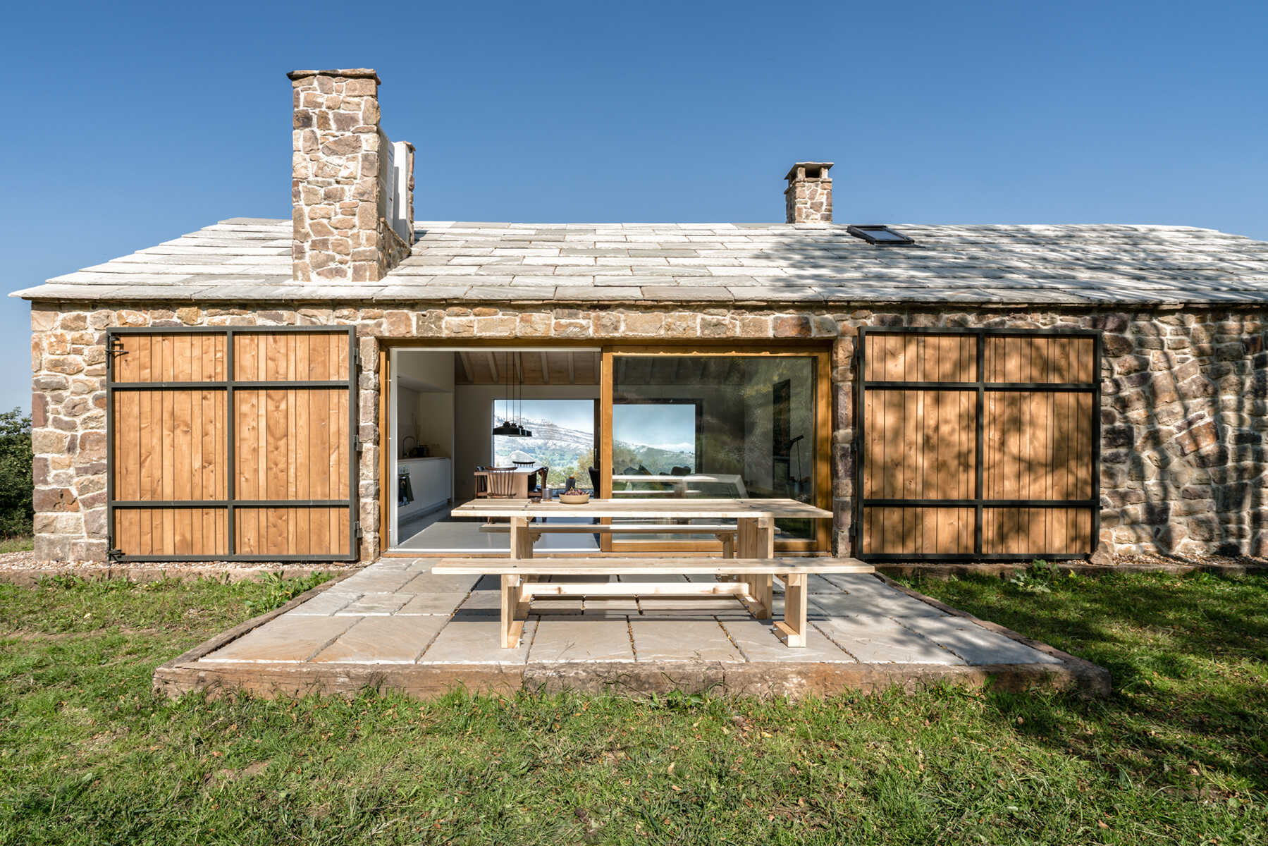 A stone cottage with sliding glass doors that open to a patio.