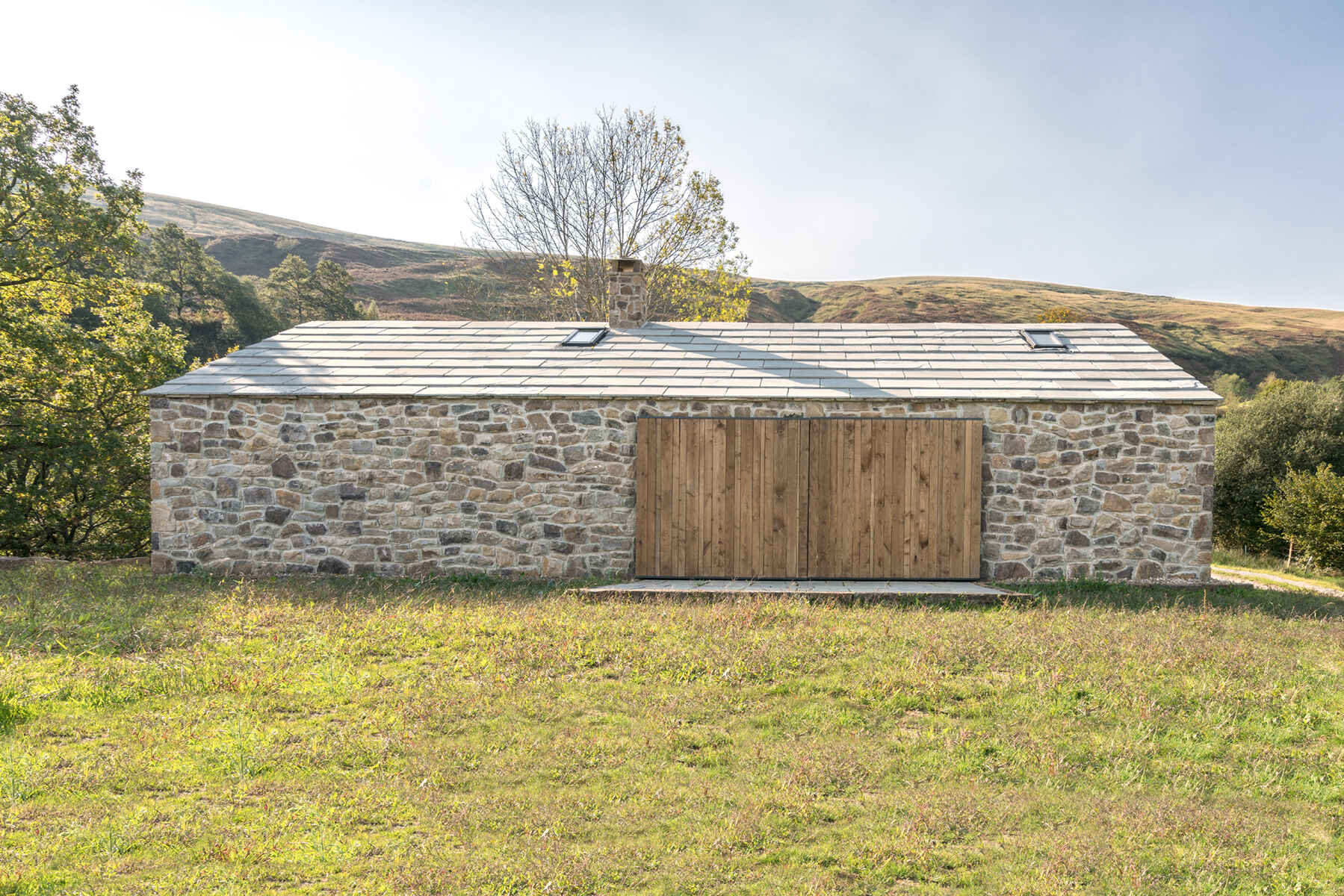 A modern stone cottage with wood sliding doors that can be closed when needed.