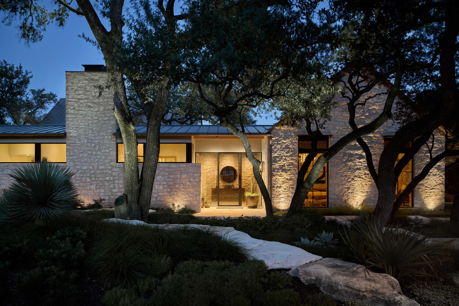 A modest street view hides a courtyard home filled with natural light, limestone, and wood by Furman & Keil Architects.