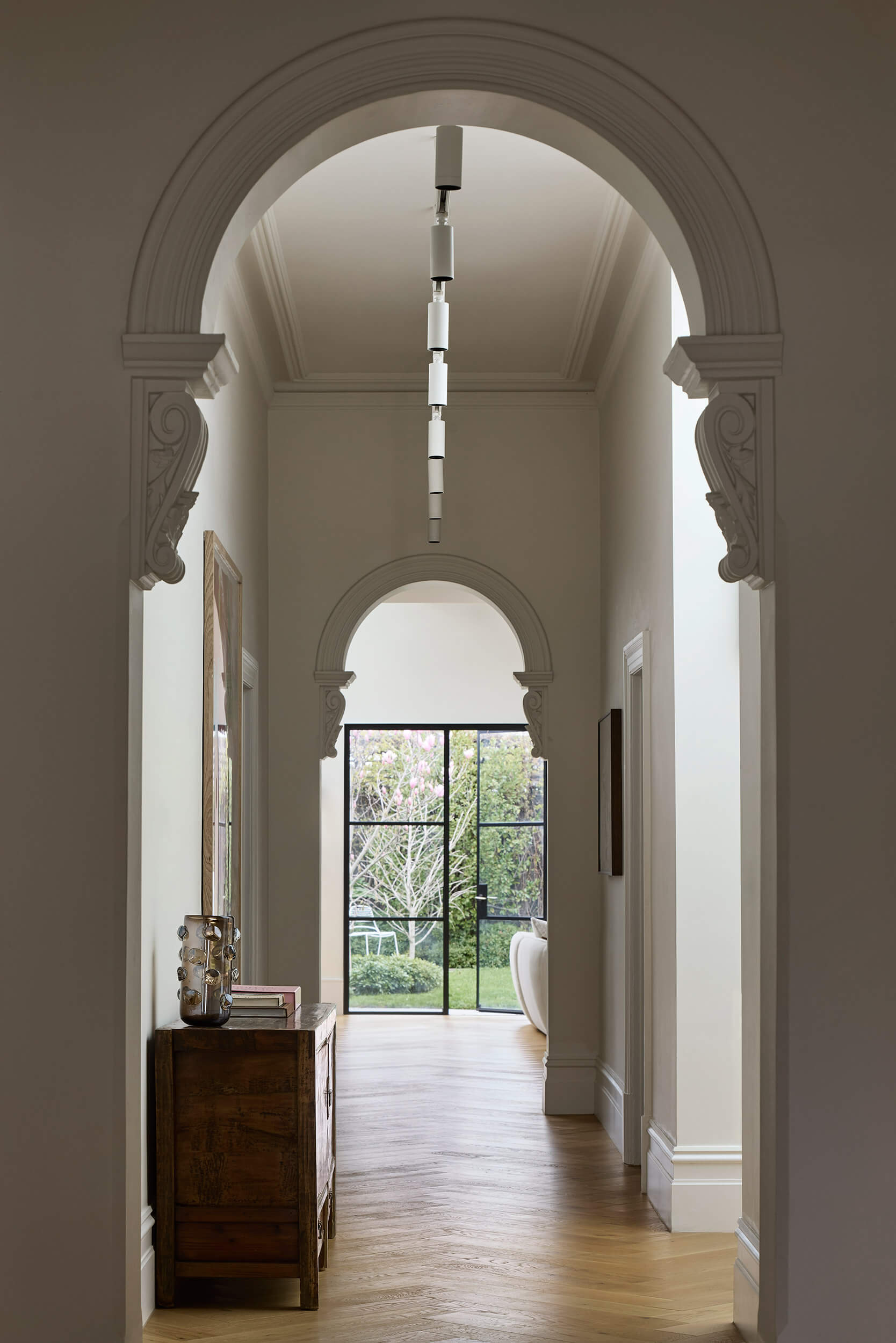 Herringbone flooring and framed views define the hallway of this Australian home, connecting past and present effortlessly.