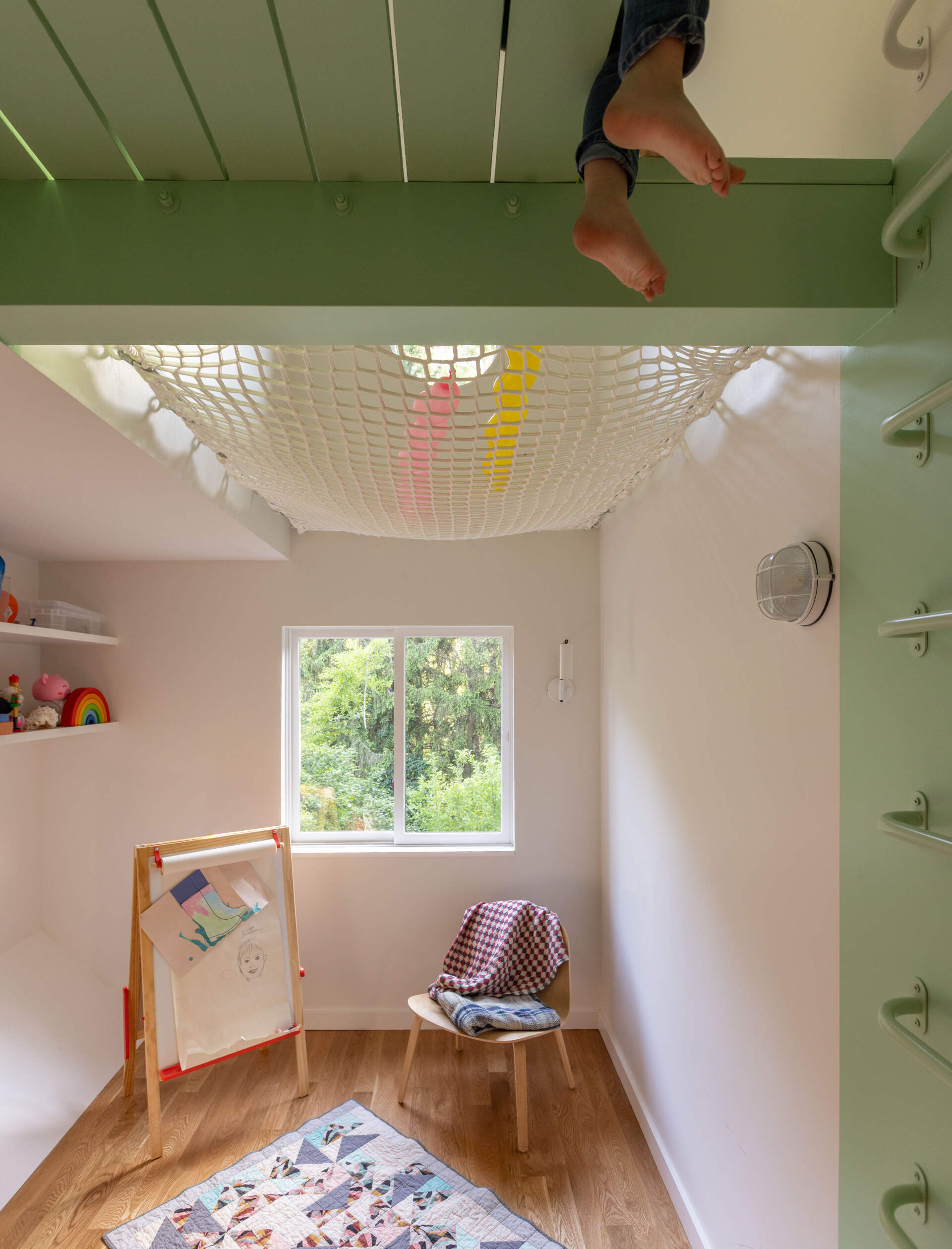 A double-height playroom with a ladder, net, and porthole window adds whimsy and fun.