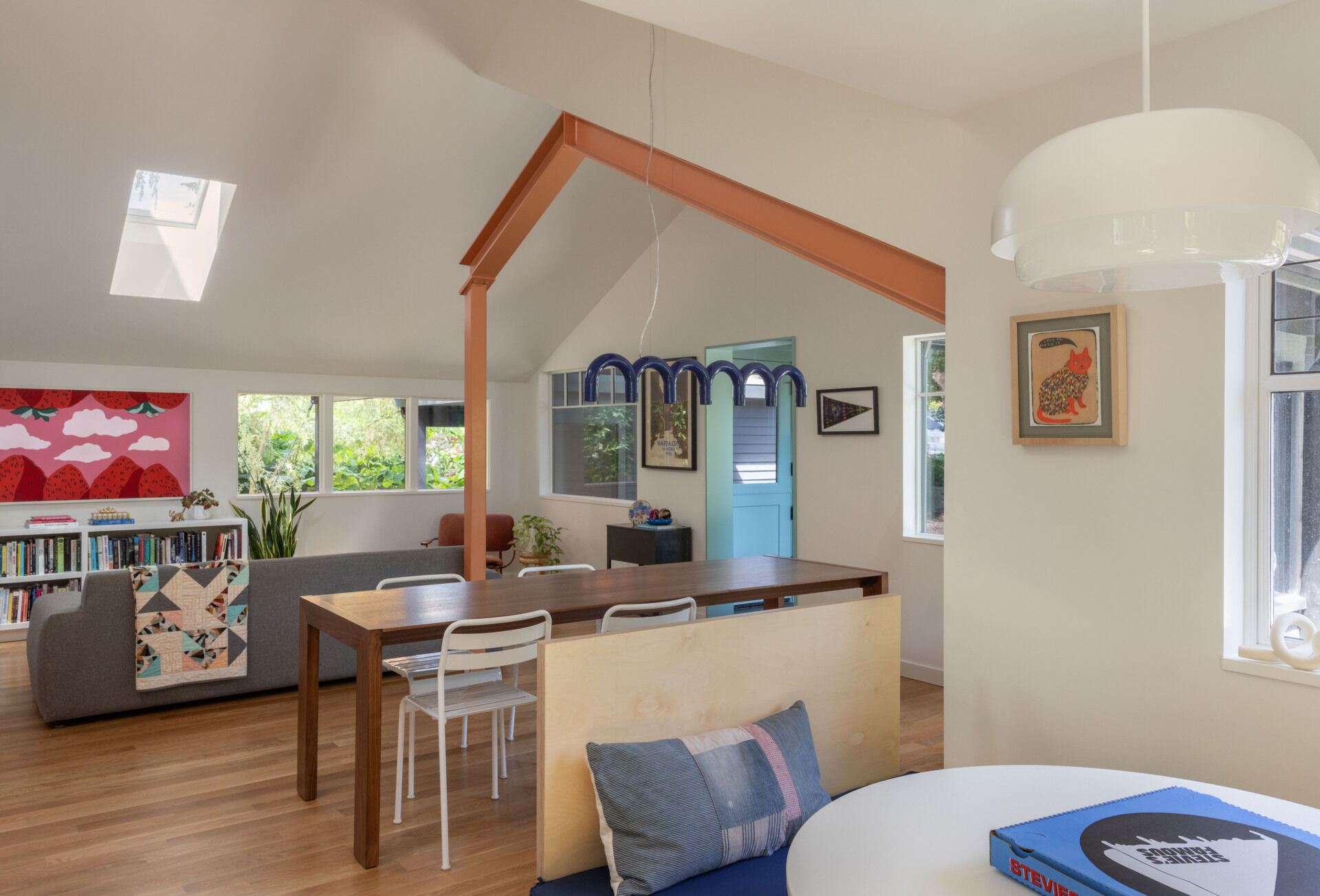 BEFORE - Open living and dining spaces now feature coral-painted steel beams and floor-to-ceiling bookshelves.