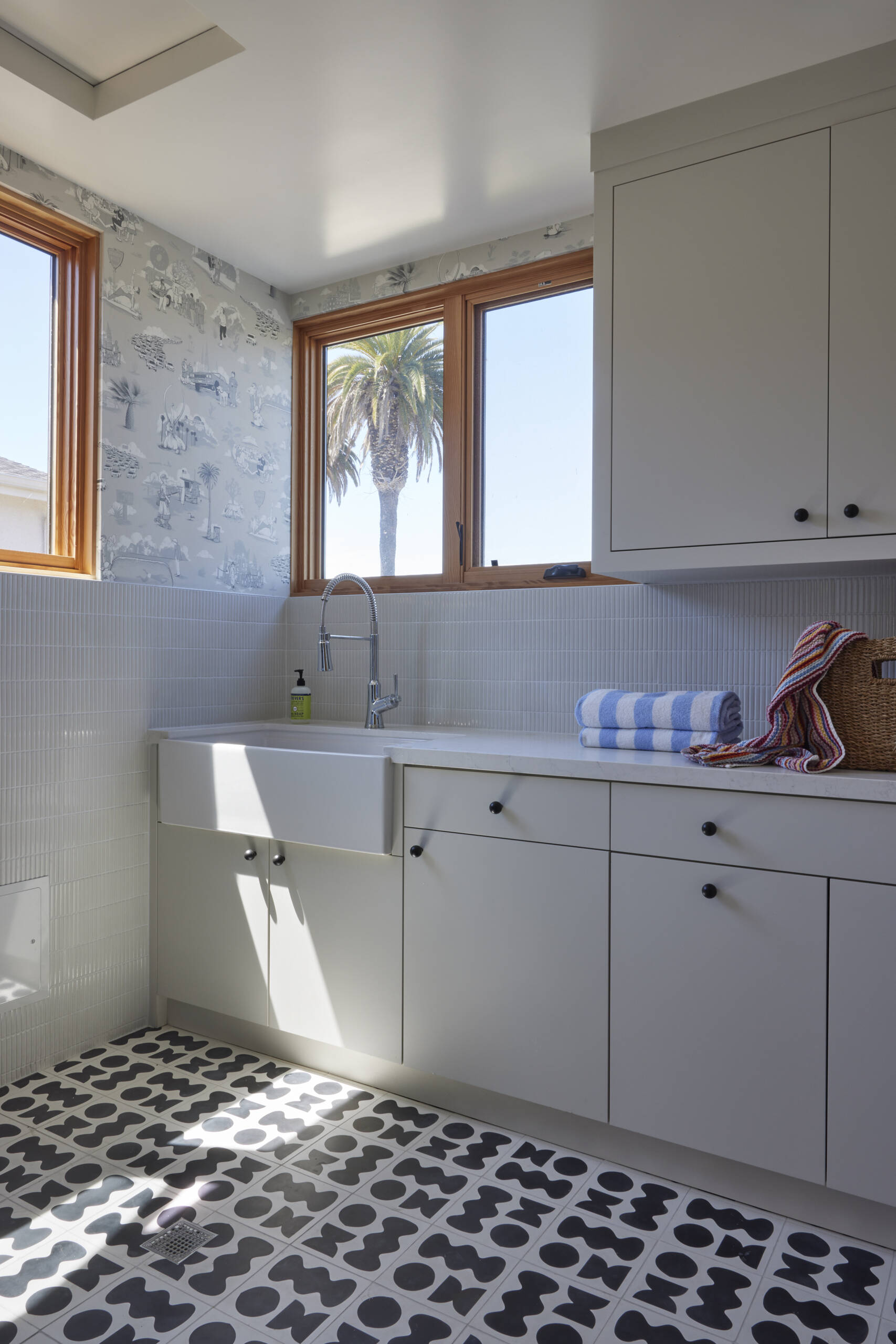 Los Angeles–themed toile wallpaper and graphic floor tiles transforms laundry into a visual experience, turning a chore space into something memorable.