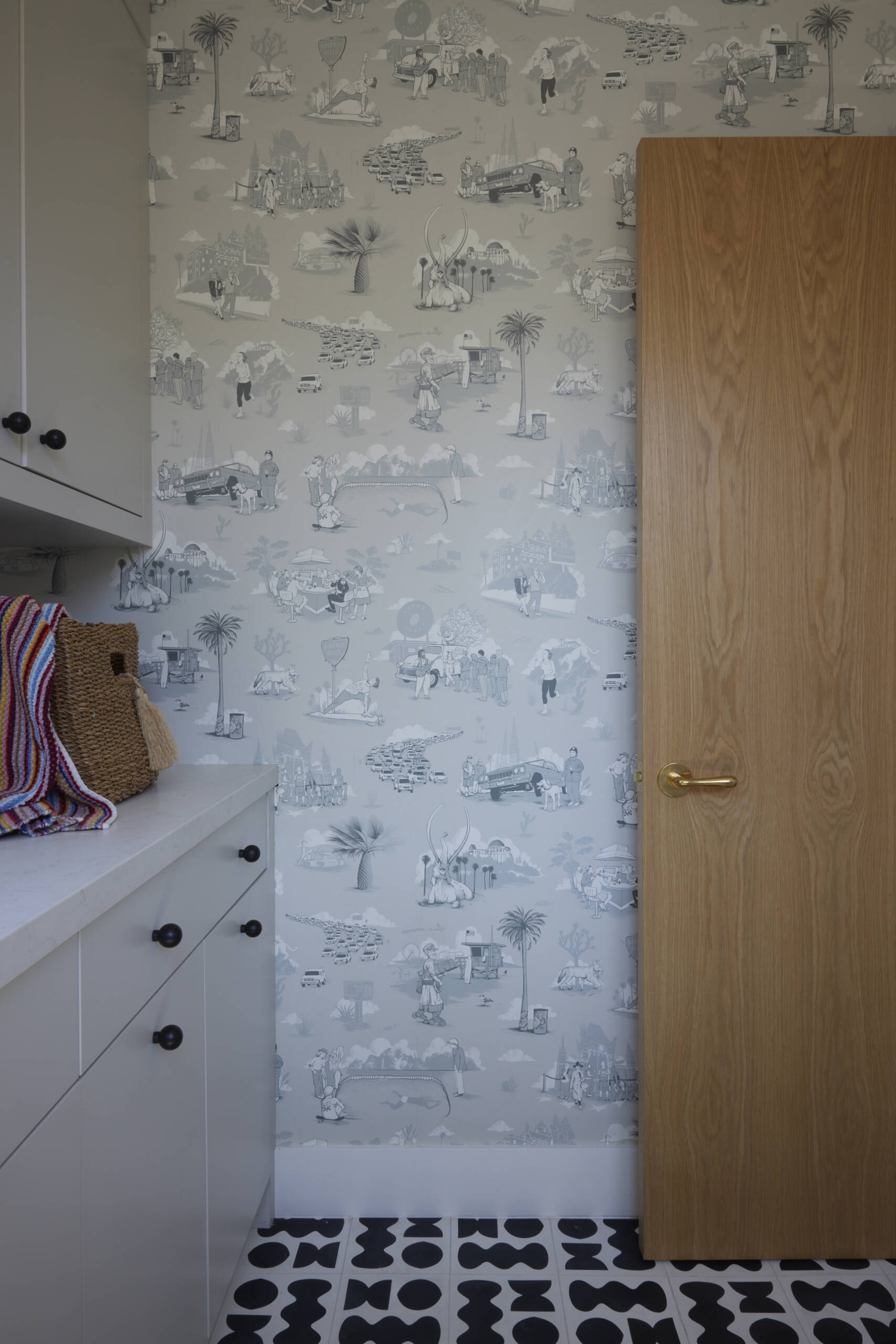 Los Angeles–themed toile wallpaper and graphic floor tiles transforms laundry into a visual experience, turning a chore space into something memorable.