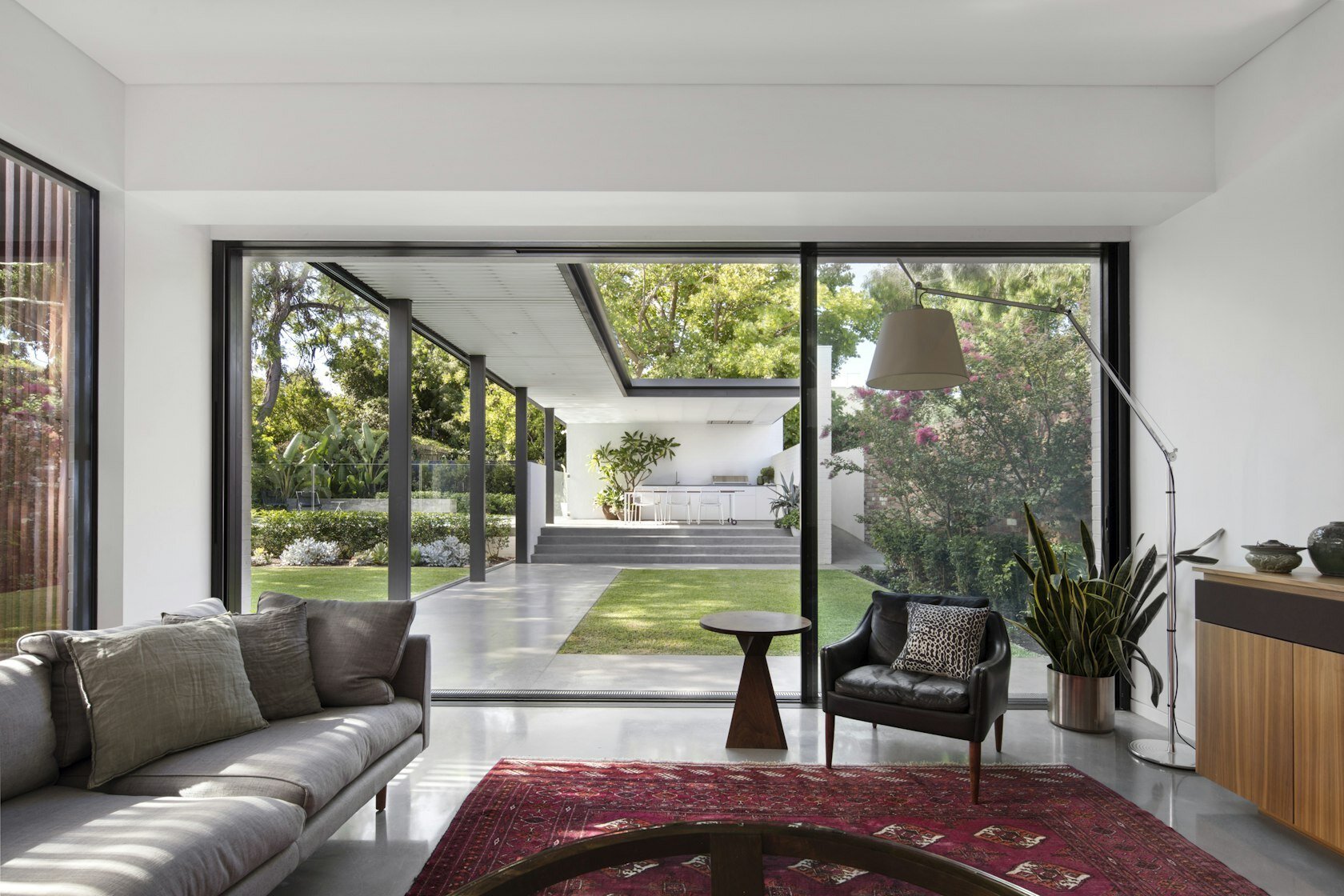 The living room opens entirely to the backyard through concealed sliding glass doors for seamless indoor-outdoor living.