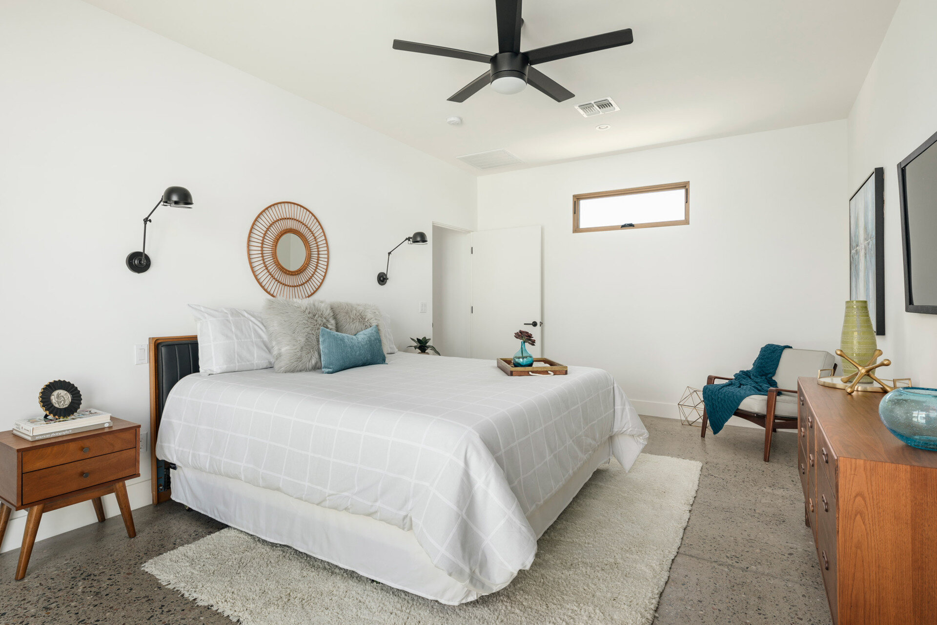 In the master bedroom, warmth comes from simple details: wood-framed windows, matching furniture, and a soft interplay of texture with exposed aggregate concrete floors. The result is serene but tactile, where every material has purpose and weight.