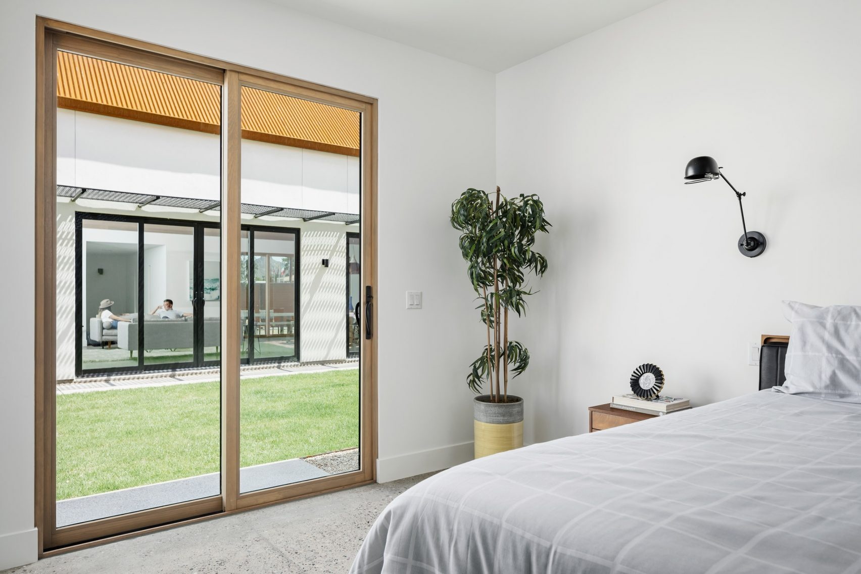 In the master bedroom, warmth comes from simple details: wood-framed windows, matching furniture, and a soft interplay of texture with exposed aggregate concrete floors. The result is serene but tactile, where every material has purpose and weight.