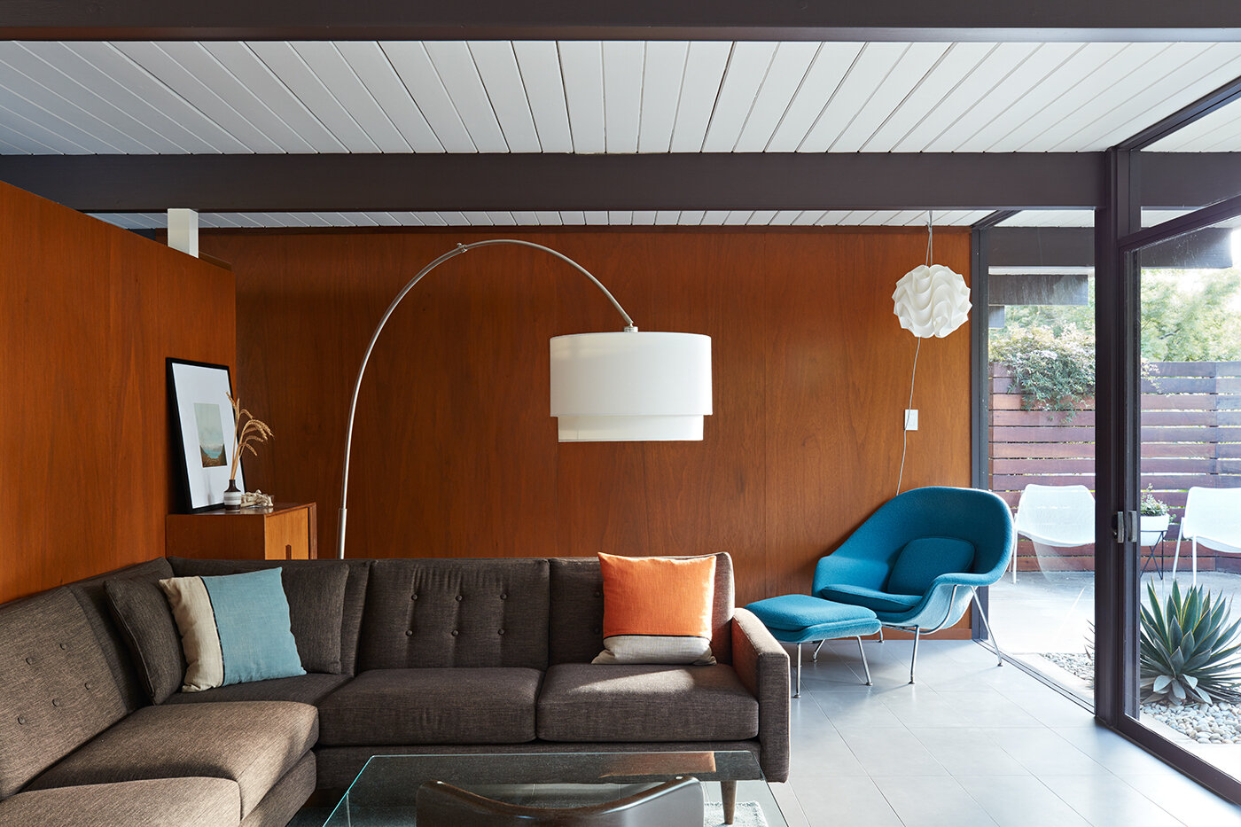 Warm wood paneling and radiant heated floors bring cozy sophistication to this mid-century living room.